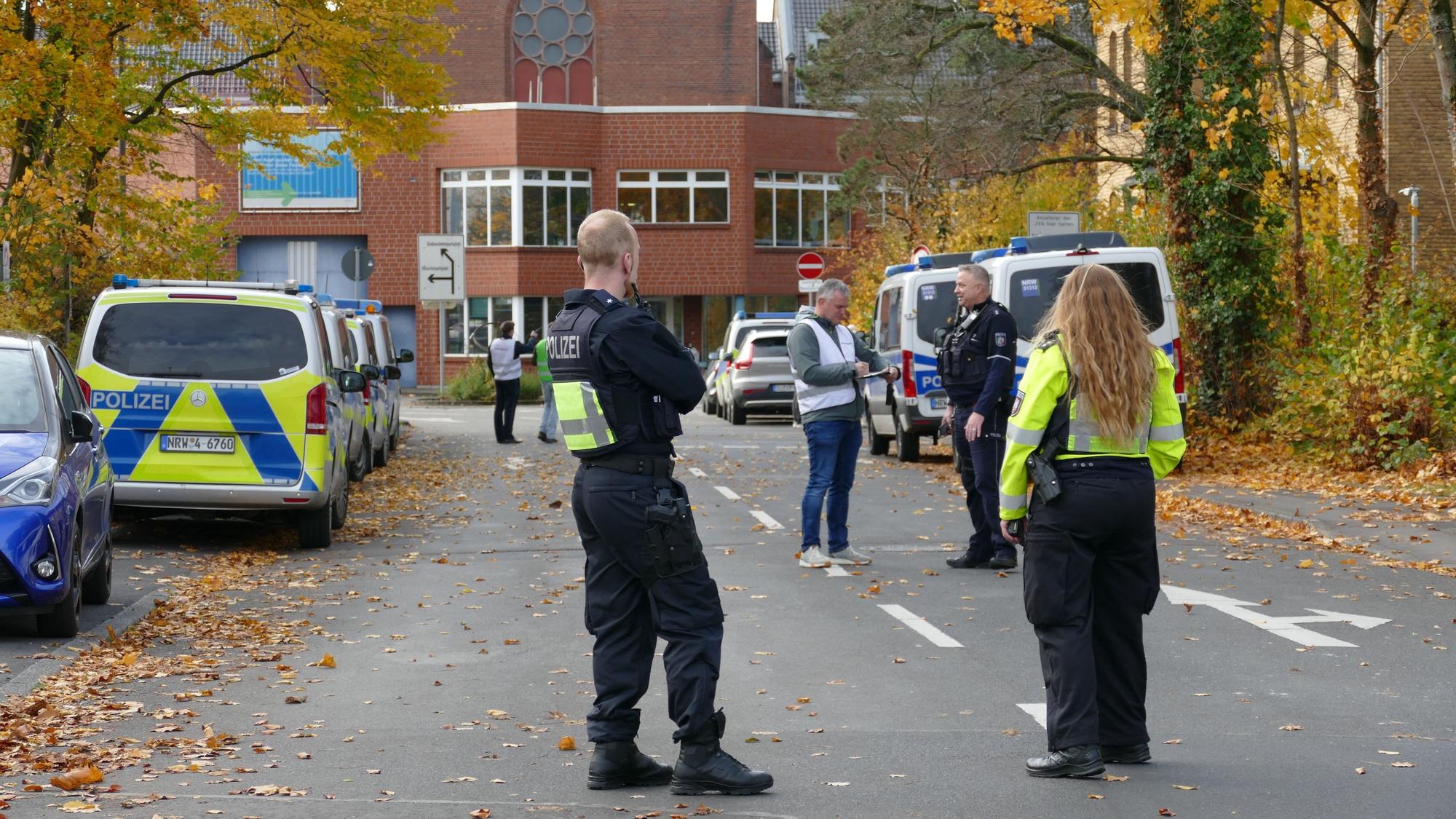 Polizistinnen und Polizisten stehen in der Zufahrt der JVA an der Luisenstraße in Siegburg.