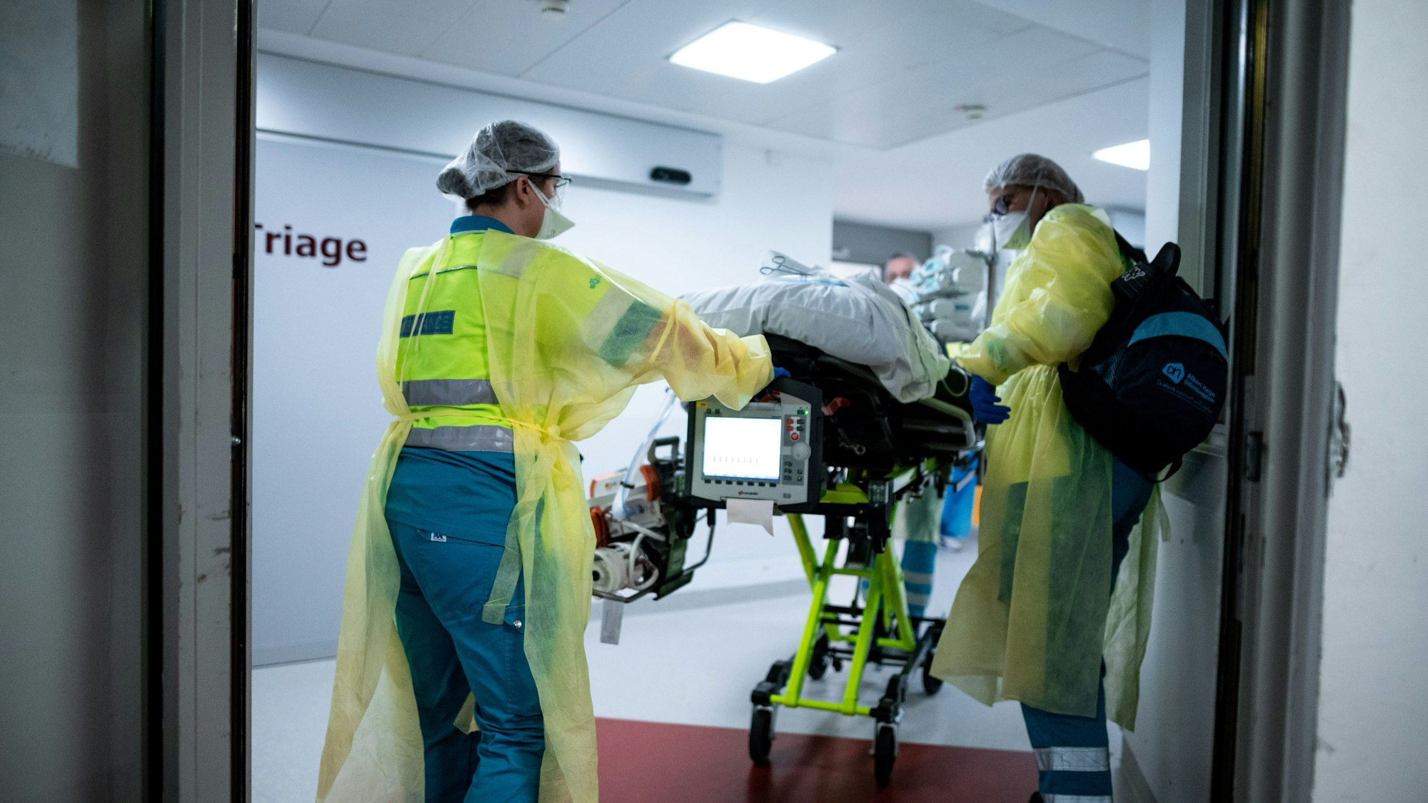 Sanitäter schieben einen Patienten auf einer Trage durch ein Krankenhaus.