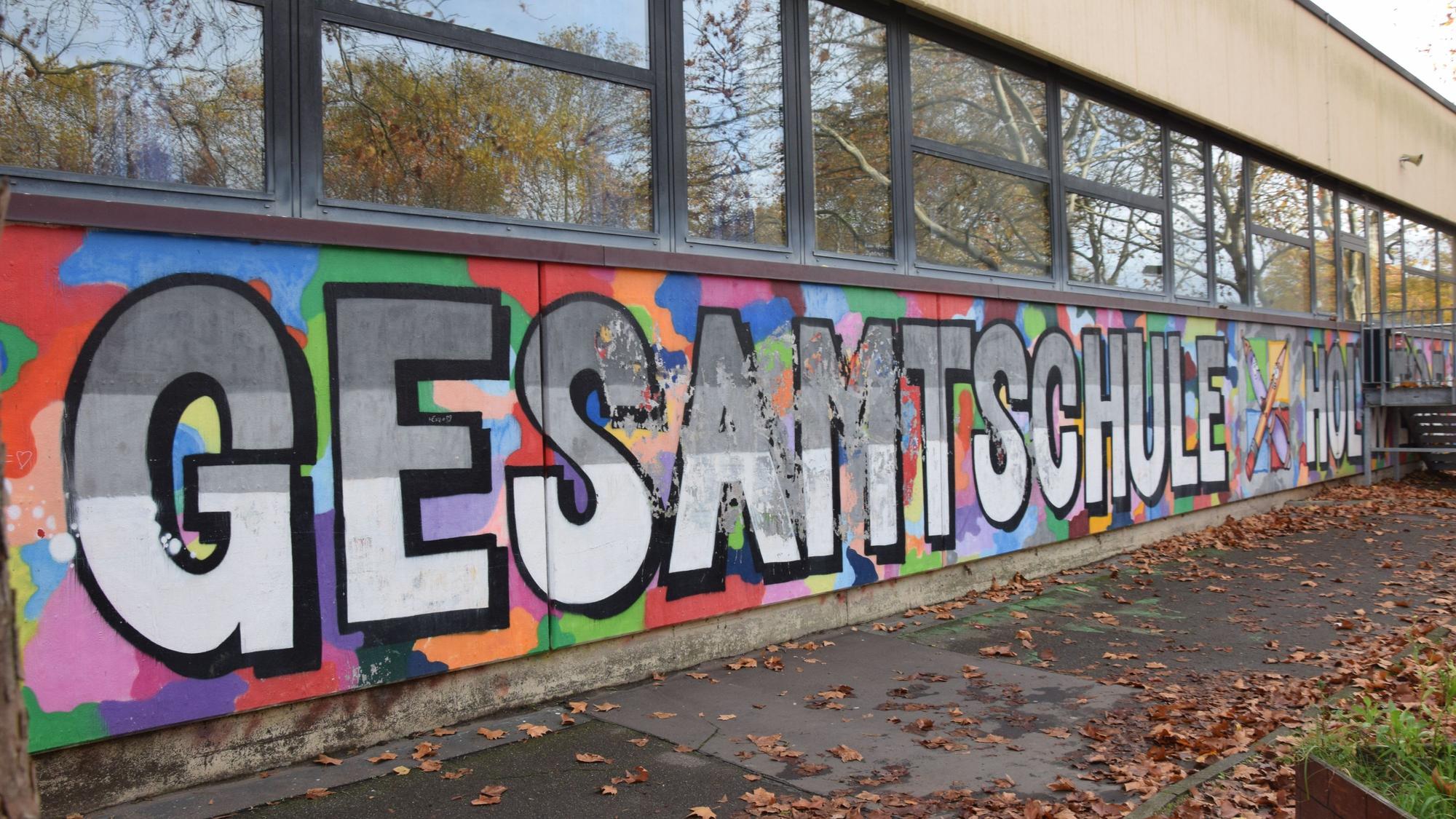 An der Fassade eines Flachbaus steht in großen Lettern Gesamtschule Holweide.