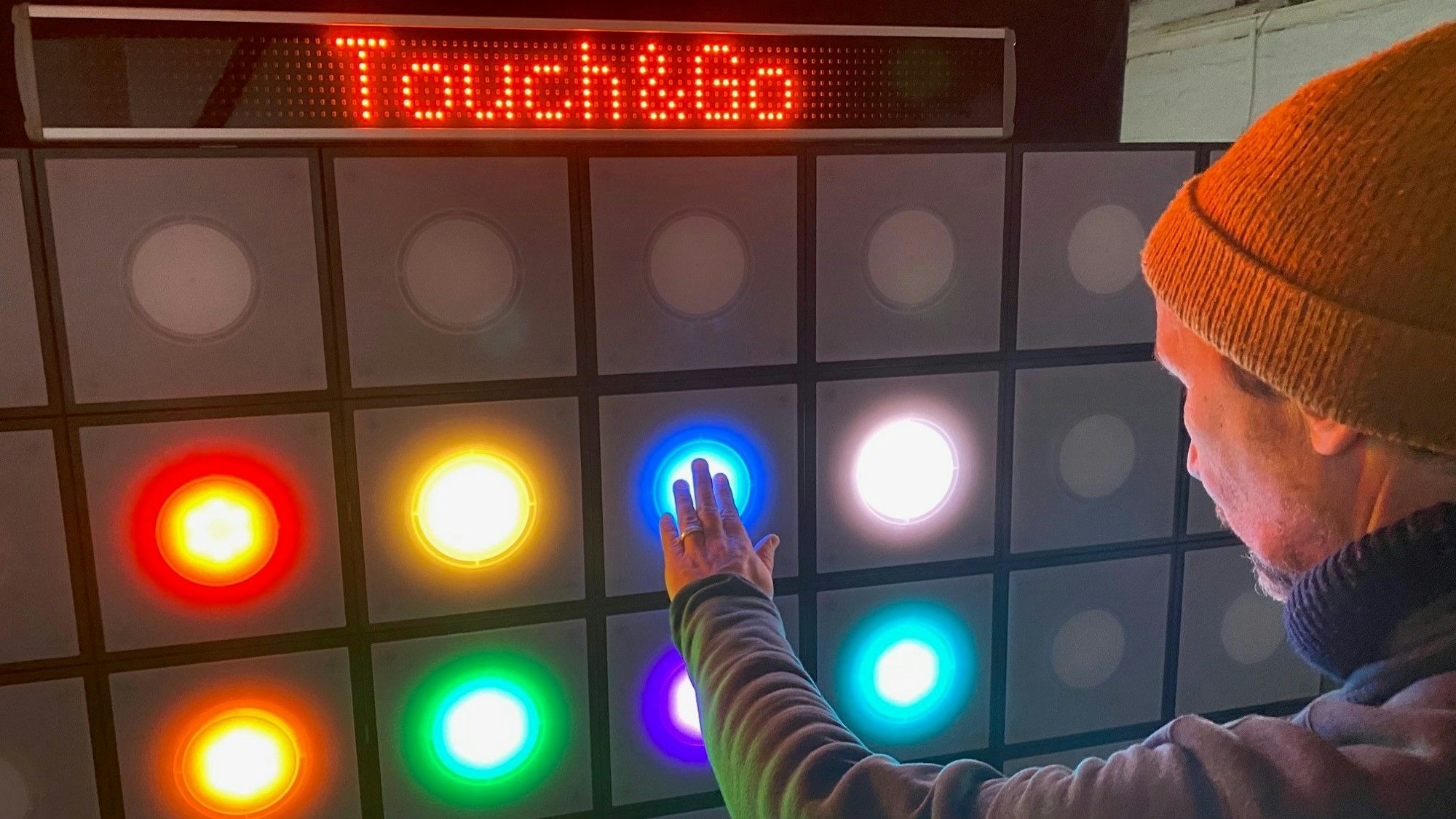 Zu sehen ist ein buntes Display, das ein Mann bedient.