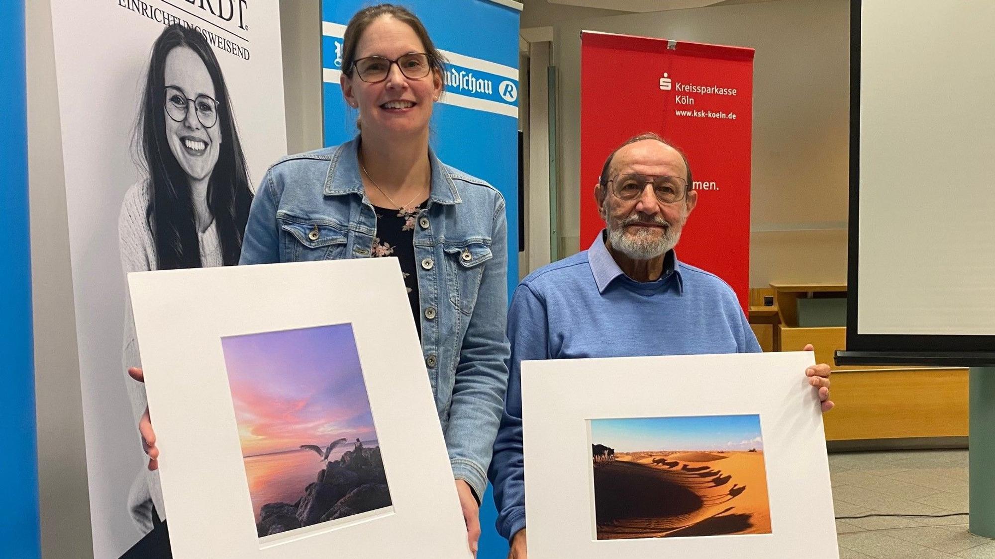 Zu sehen sind Katharina Stettien und Robert Hanke, die ihre Bilder in den Händen halten.