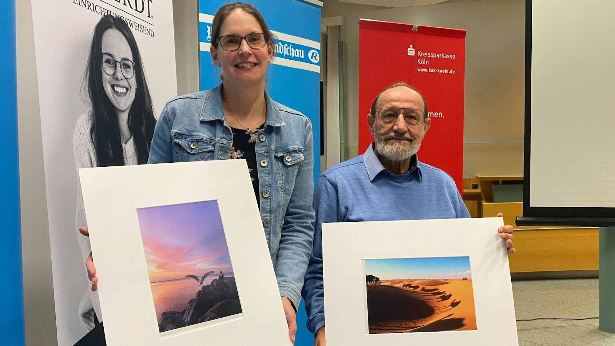 Zu sehen sind Katharina Stettien und Robert Hanke, die ihre Bilder in den Händen halten.