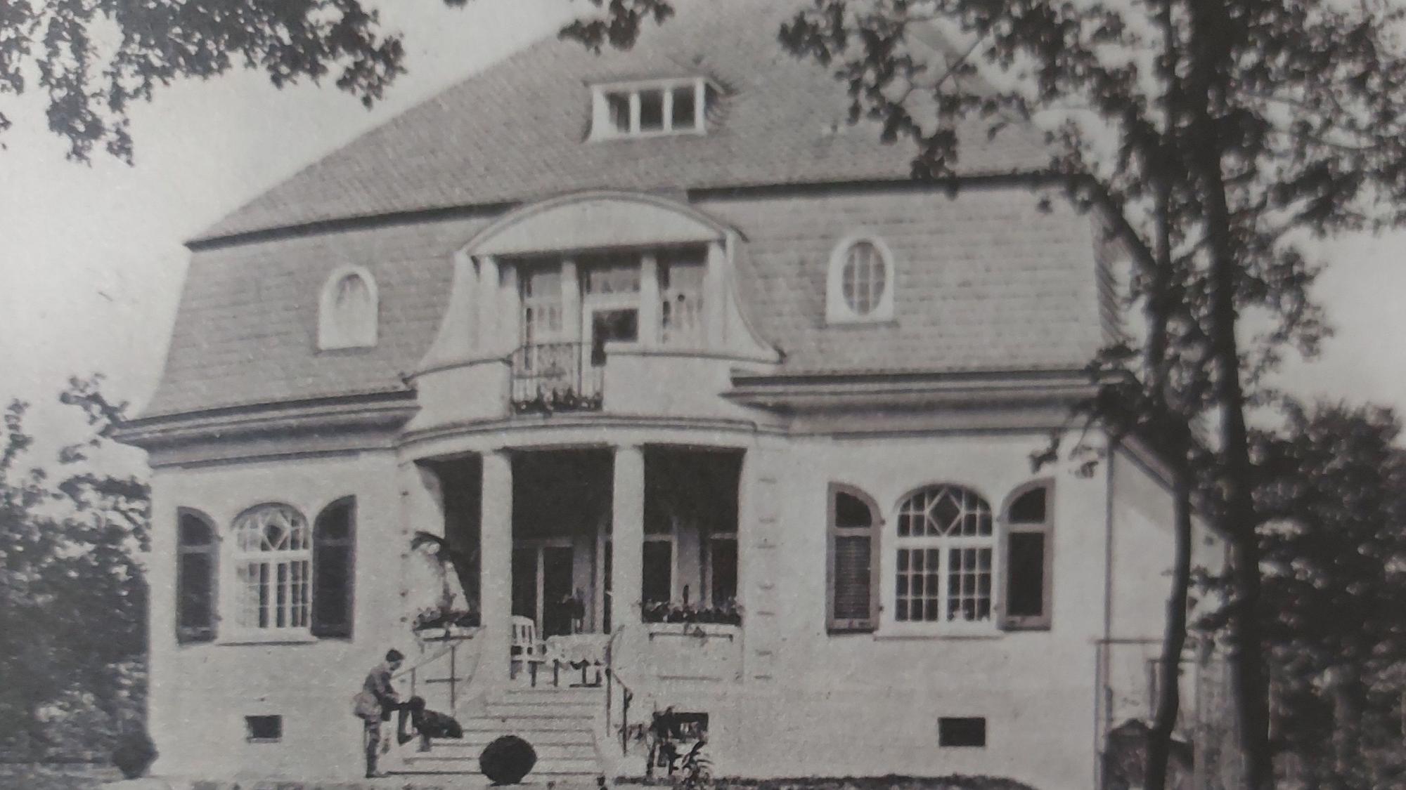 Eine Villa mit Walmdach und einem herrschaftlichen Treppenaufgang mit Säuleneingang.