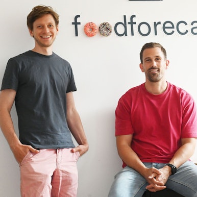 Zwei junge Männer lächeln in die Kamera.