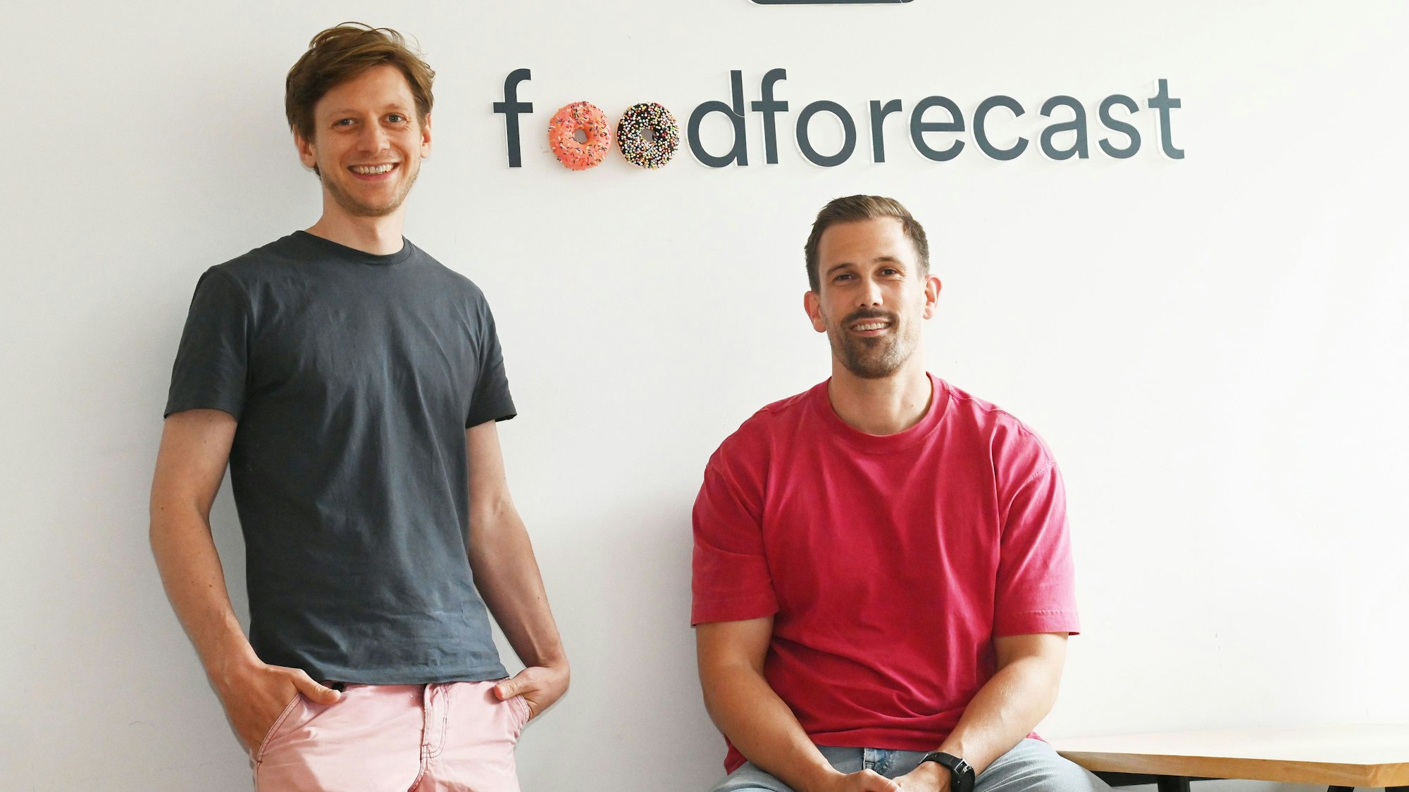 Zwei junge Männer lächeln in die Kamera.