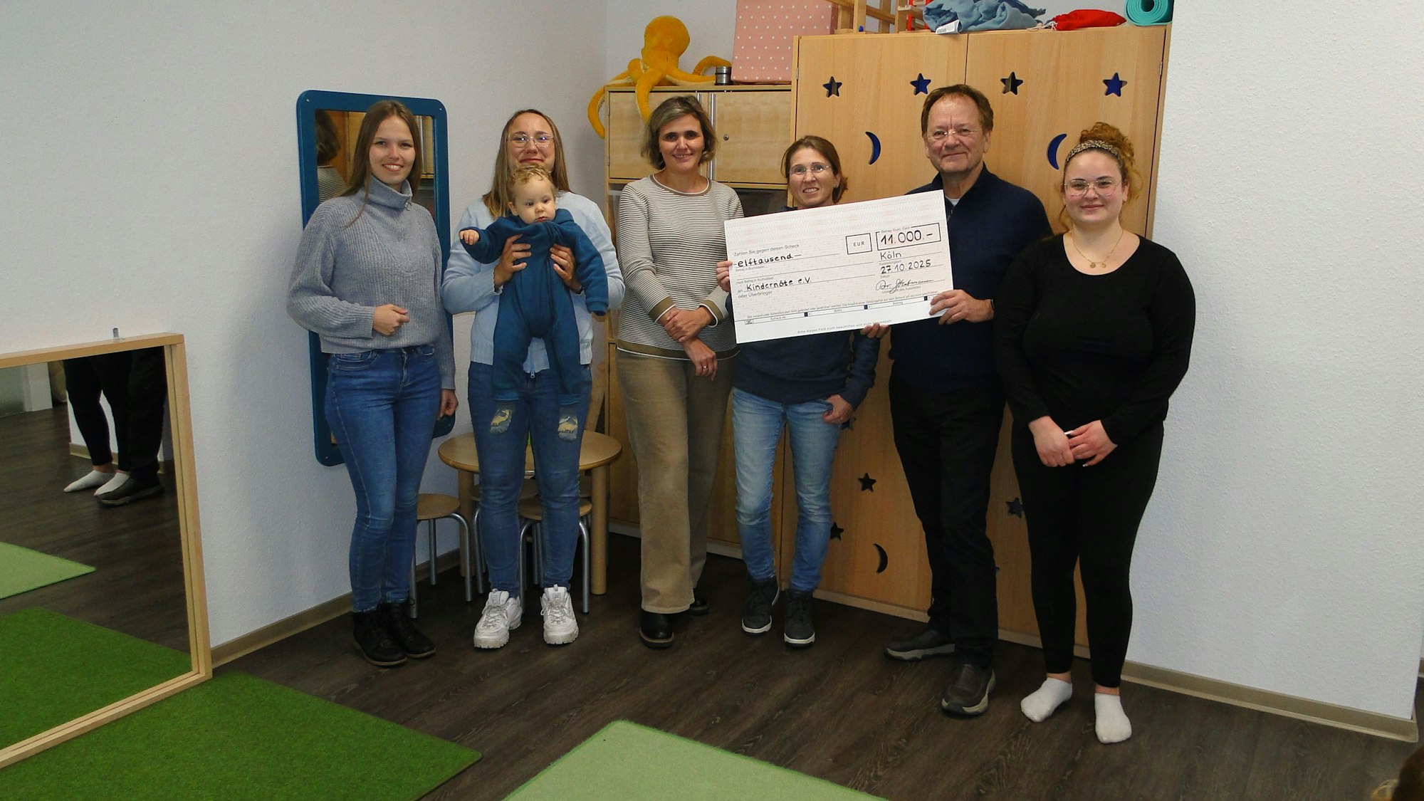 Franz-Heinrich Stratmann (2. von rechts) aus dem Vorstand der Rolf-Lappe-Stiftung übergab einen symbolischen Scheck über die Fördersumme an Mitarbeitende und Teilnehmende des Eltern-Kind-Cafés.