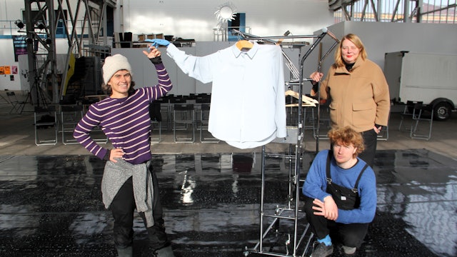 Zwei Frauen und ein Mann stehen in einer großen Halle.