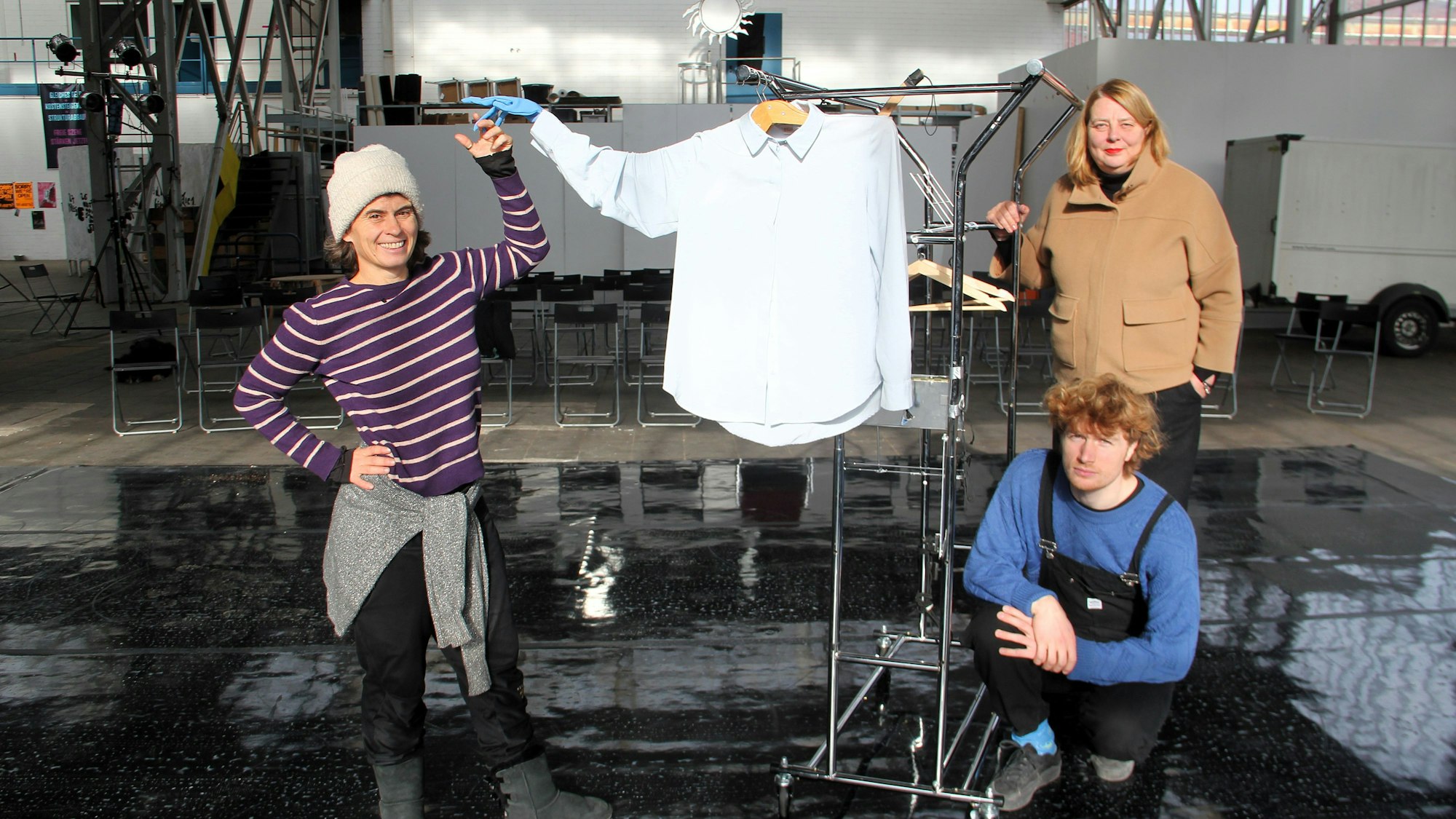 Zwei Frauen und ein Mann stehen in einer großen Halle.