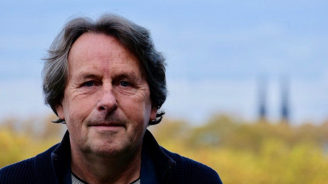 Ein Mann mit dunklem Haar schaut in die Kamera.