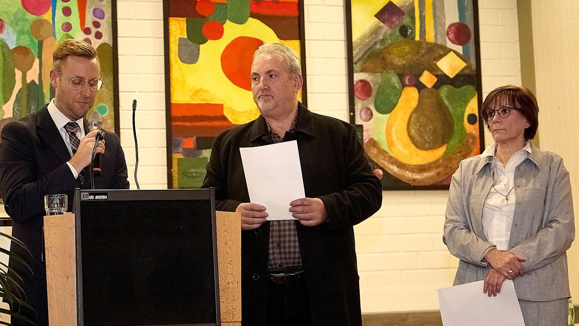 Martin Berners, der neue Bürgermeister in Hellenthal, spricht in ein Mikrofon. Rechts von ihm stehen seine Stellvertreter Franz Cremer und Barbara Wand.