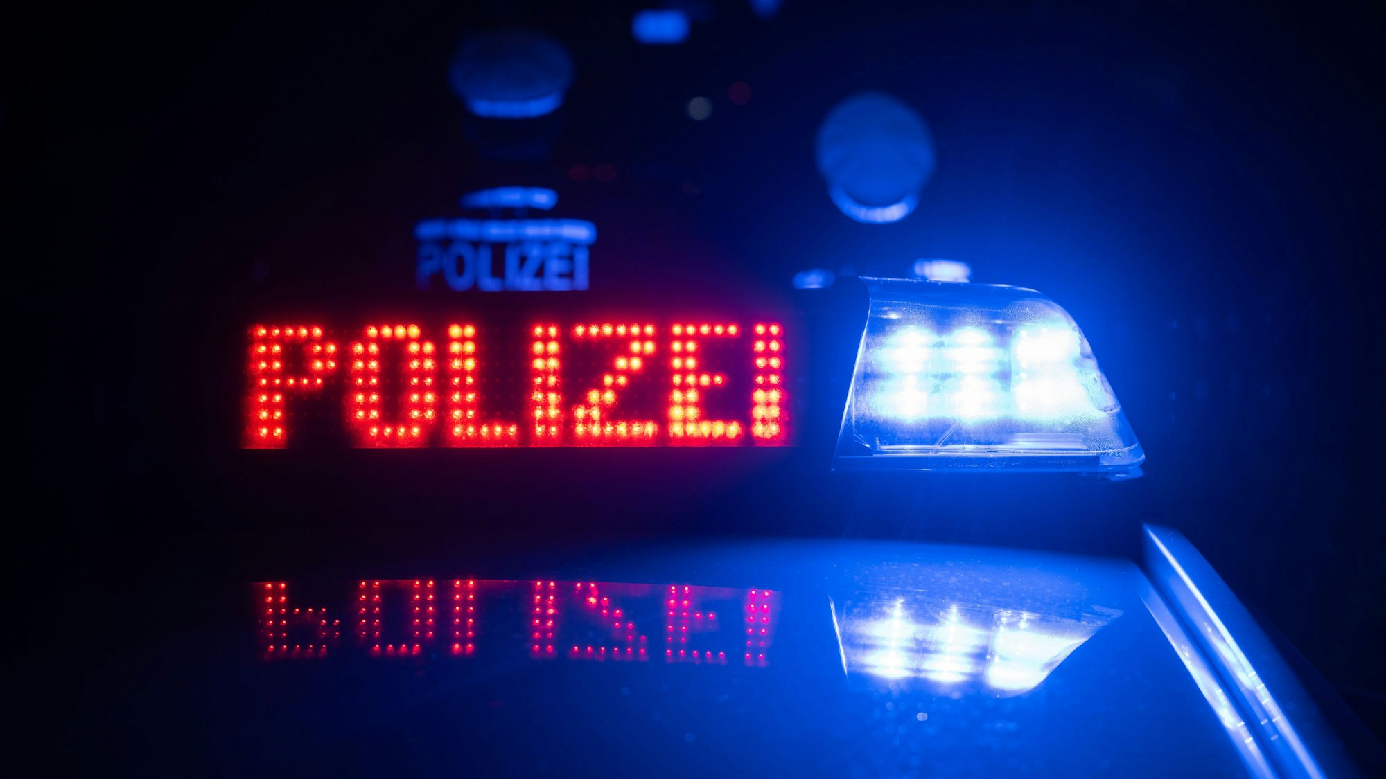 Zwei Polizisten stehen vor einem Polizeifahrzeug.