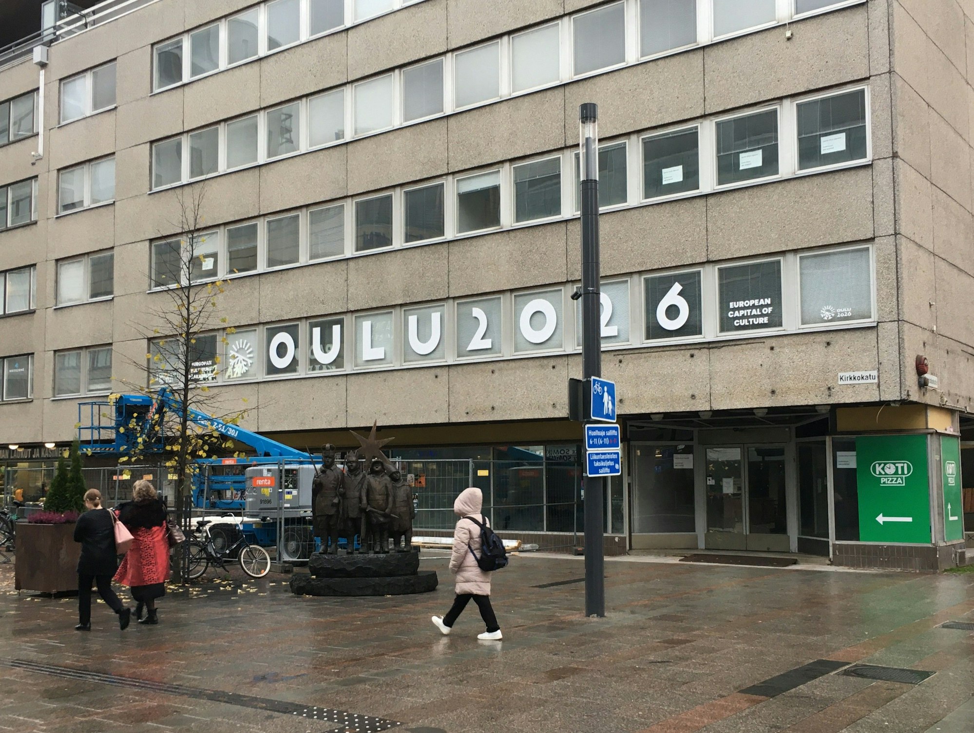 Am Ende der Fußgängerzone prangt auf den Fenstern einer grauen Hausfassade der Schriftzug „Oulu 2026“.