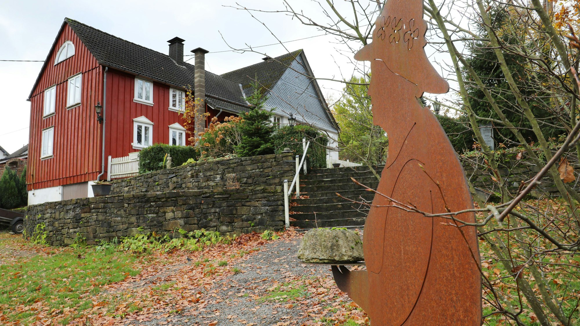 Eine Stahlfigur mit einem Kuchen in den Händen steht vor dem Hofcafé Kaffeekännchen bei Marienheide.