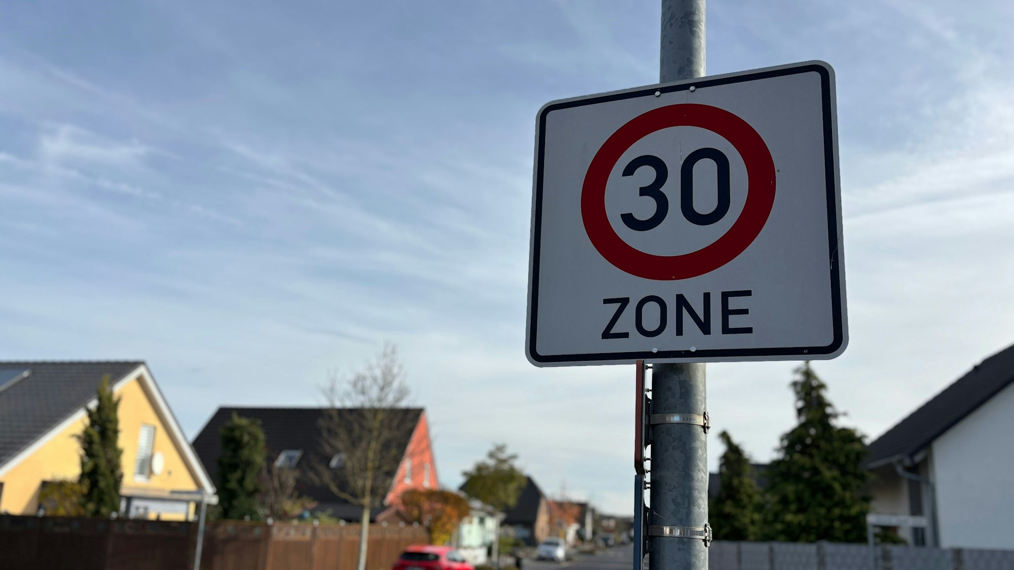 Aufnahme eines Zone-30-Verkehrsschildes mit unscharfen Häusern im Hintergrund