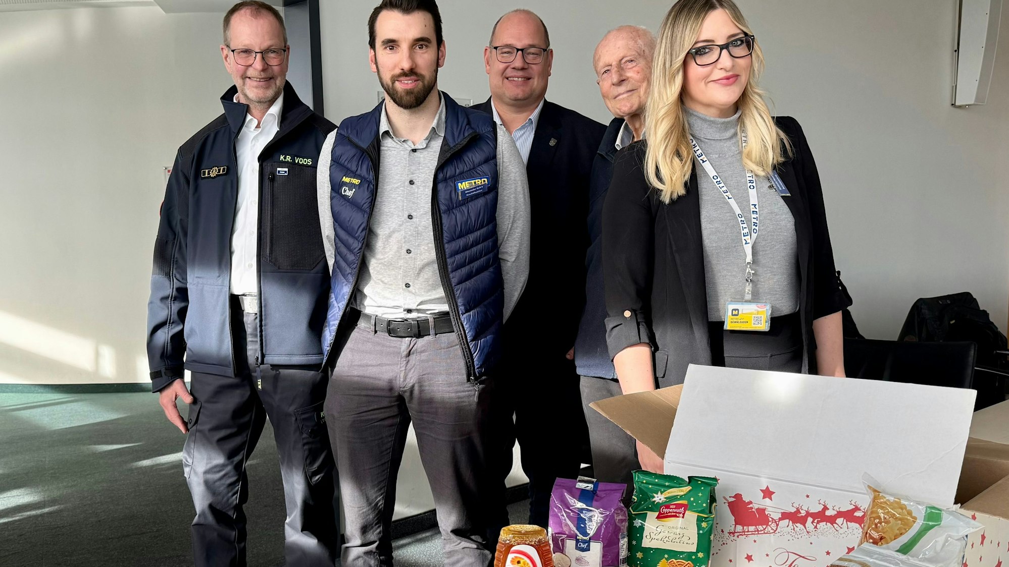 Klaus-Dieter Voos vom THW, Alexander Kohrs (Metro), Schirmherr Stefan Hebbel, Adolf Staffe von der Tafel und Nathalie-Patricia Moneta (Metro) mit dem Weihnachtspaket für 2025