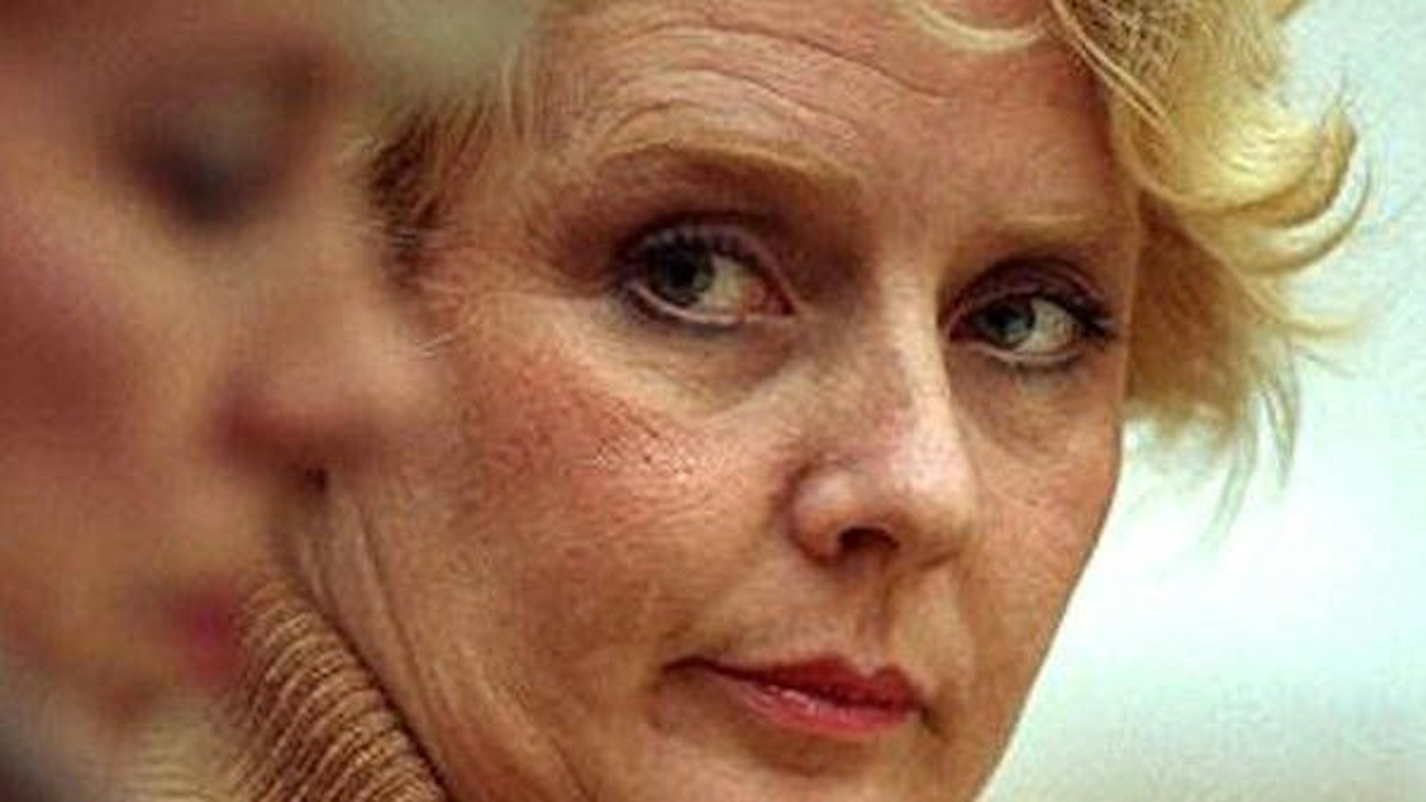 Betty Broderick mit blonden Haaren, die aufmerksam seitlich blickt