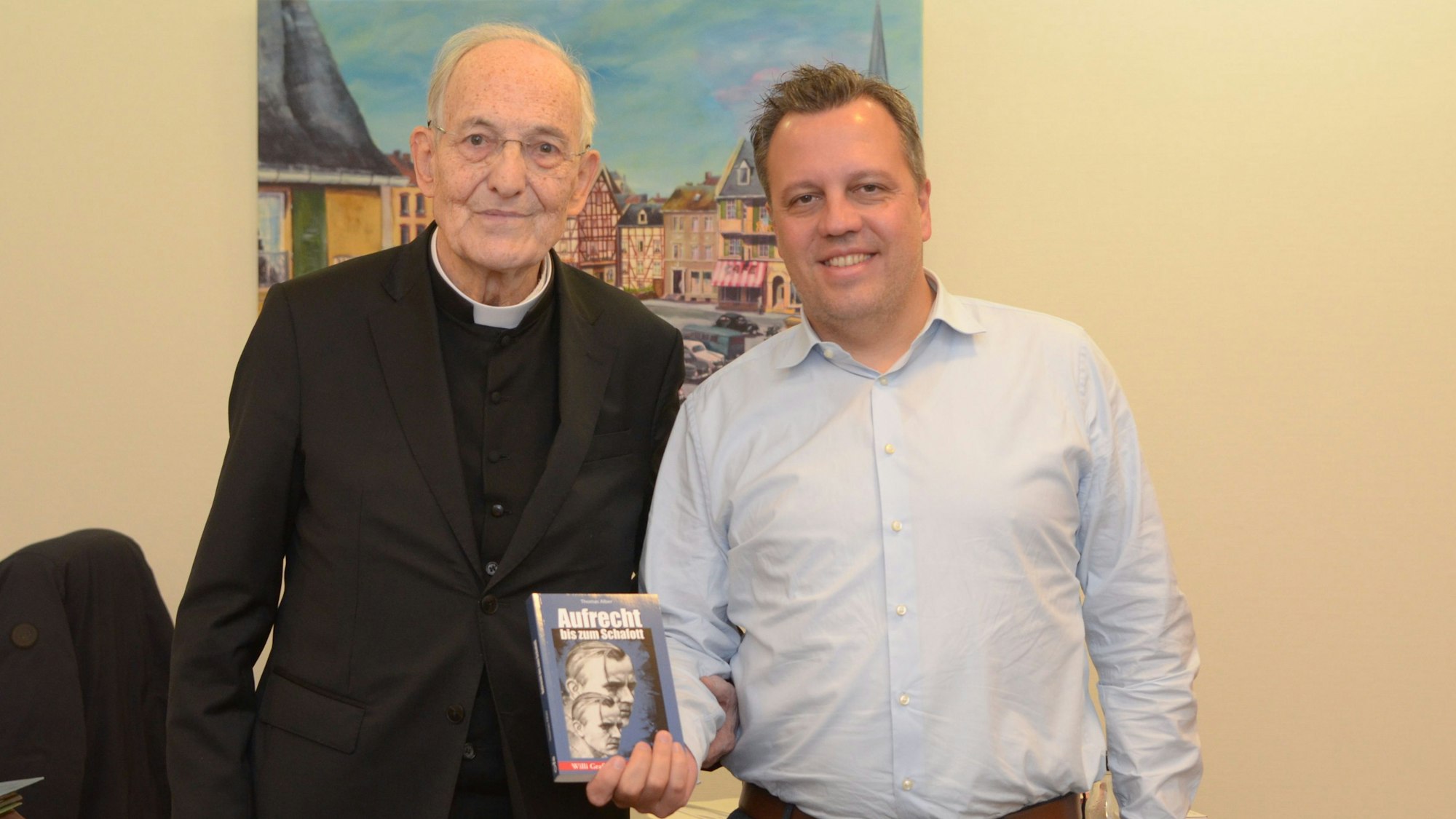 Die beiden Männer stehen nebeneinander, Reichelt hält ein Buch in der Hand.