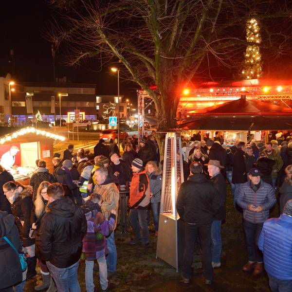 Menschen stehen und erzählen am Abend auf dem Weihnachtsmarkt Overath.