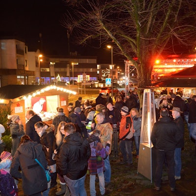 Menschen stehen und erzählen am Abend auf dem Weihnachtsmarkt Overath.