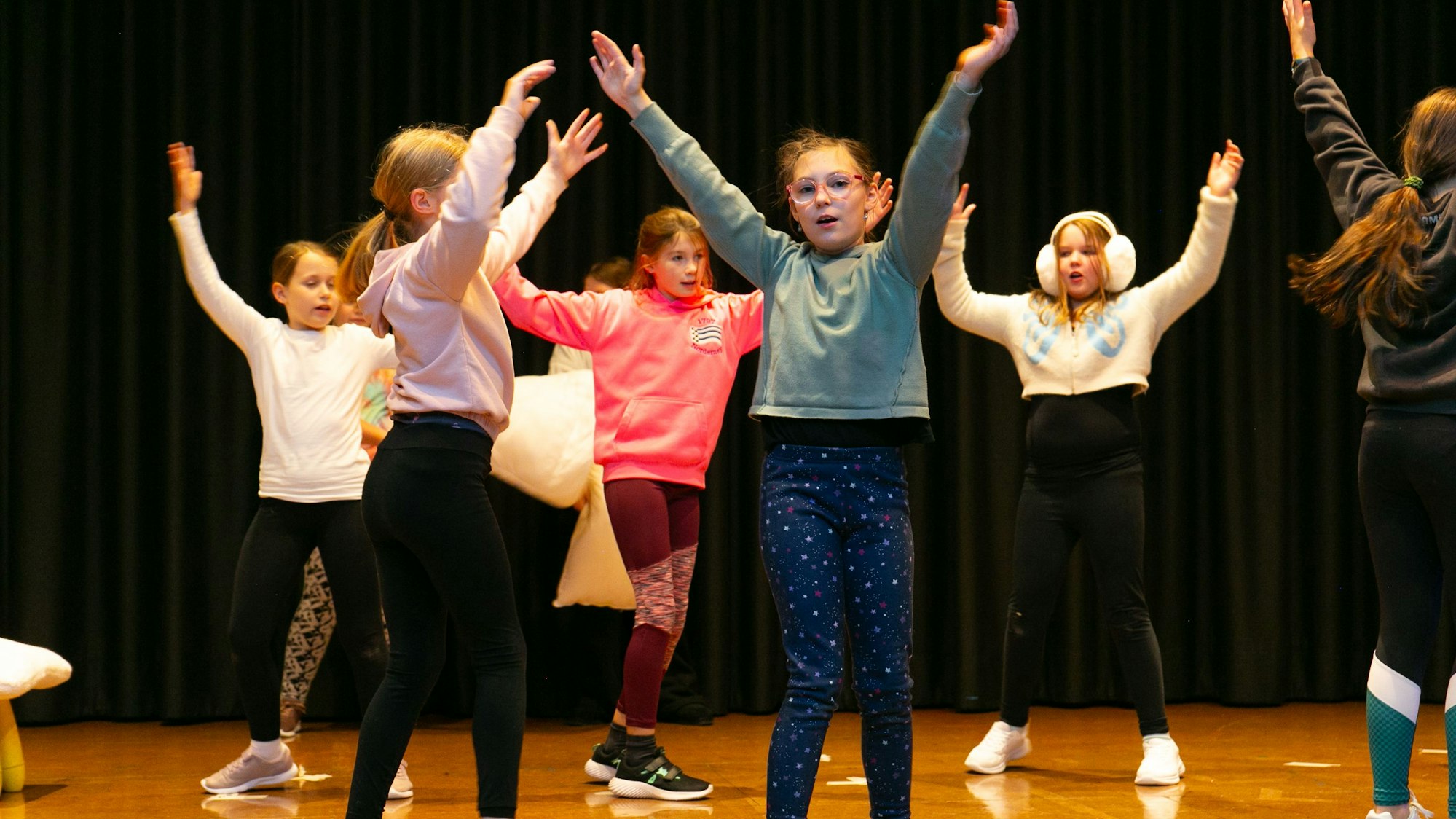 Kinder sind tanzend und singend auf einer Bühne.