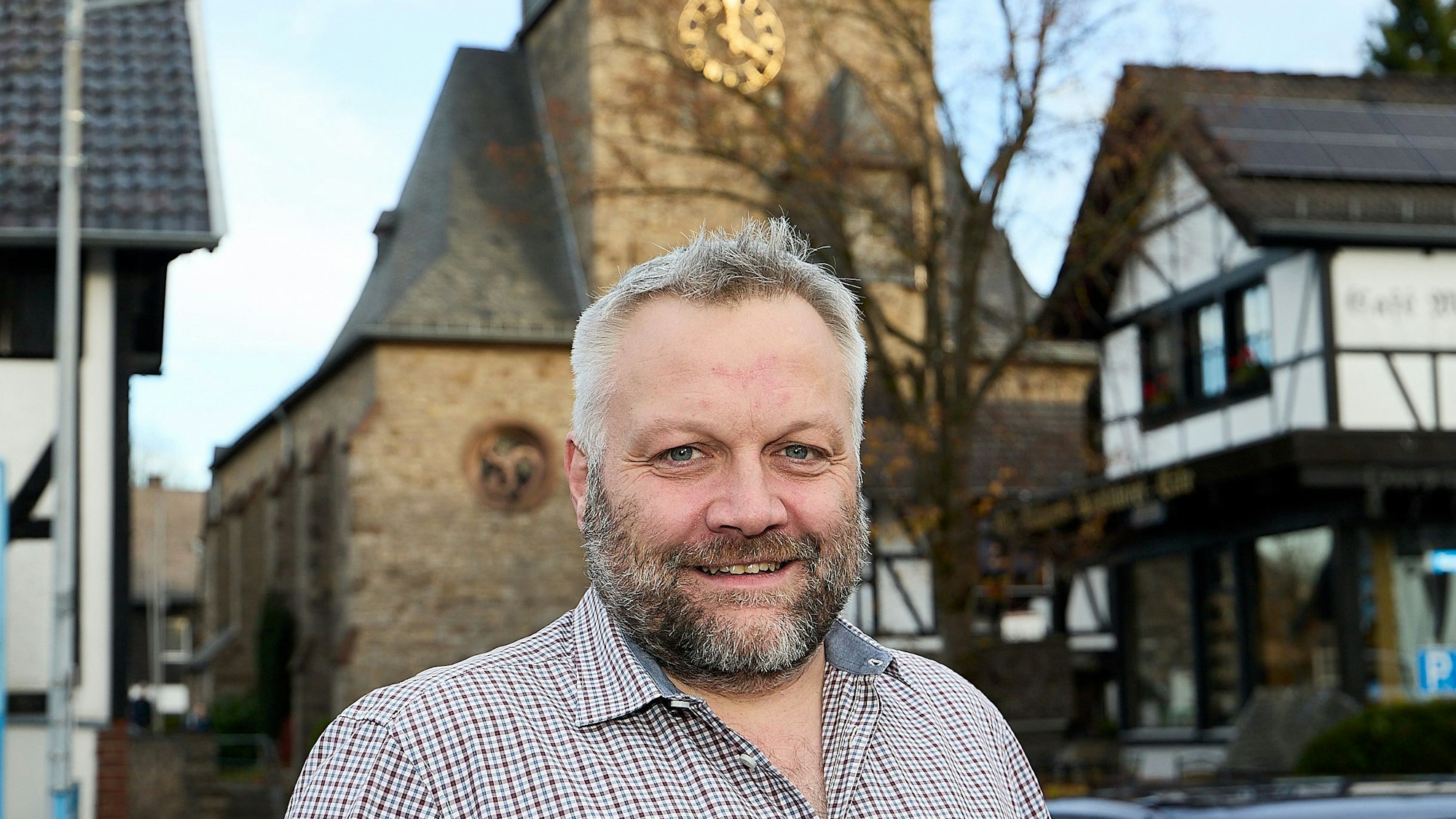 Das Bild zeigt Sebastian Pönsgen im Porträt. Im Hintergrund die Marmagener Kirche und andere Gebäude.