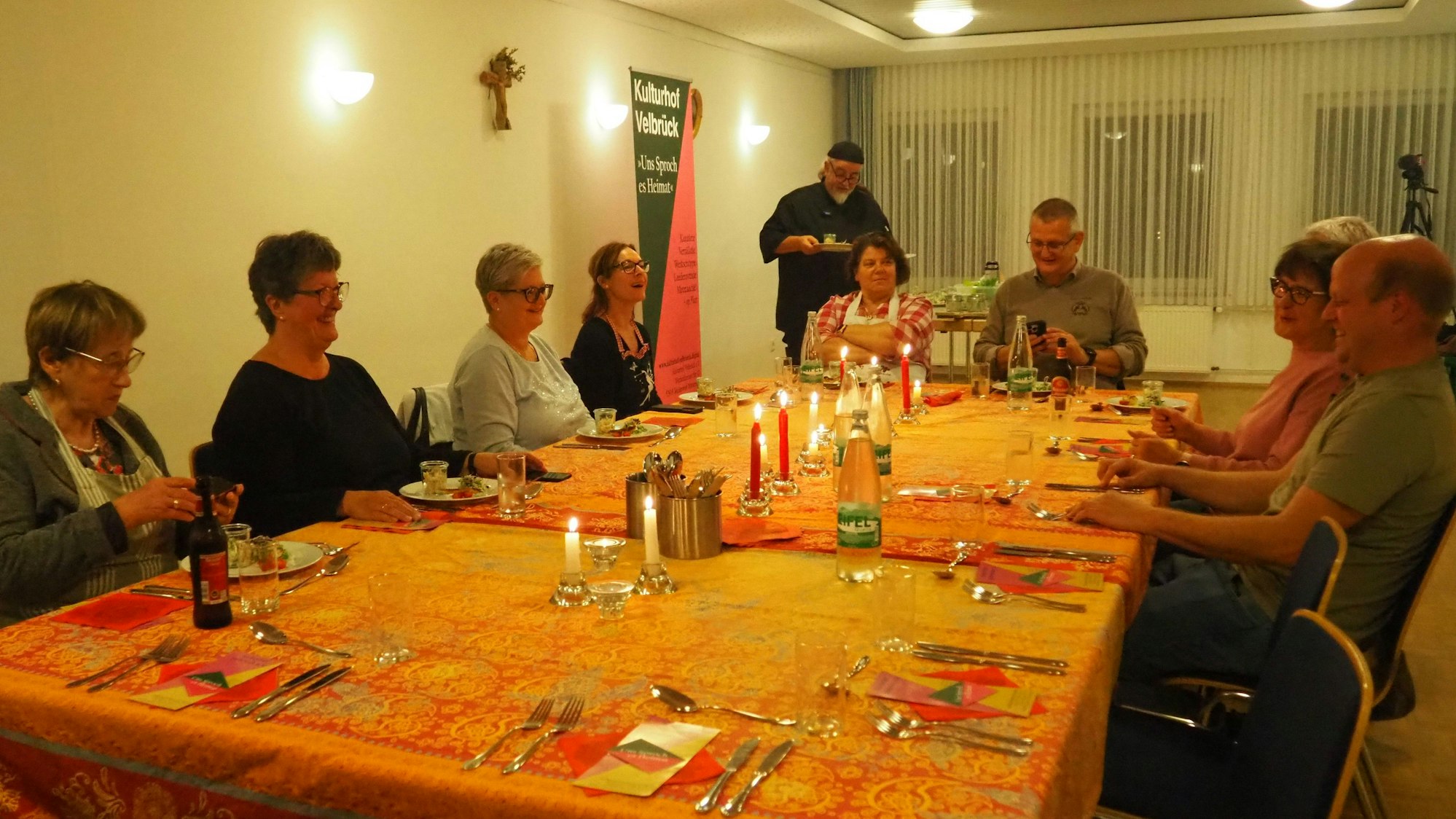Menschen sitzen an einem eingedeckten Tisch.