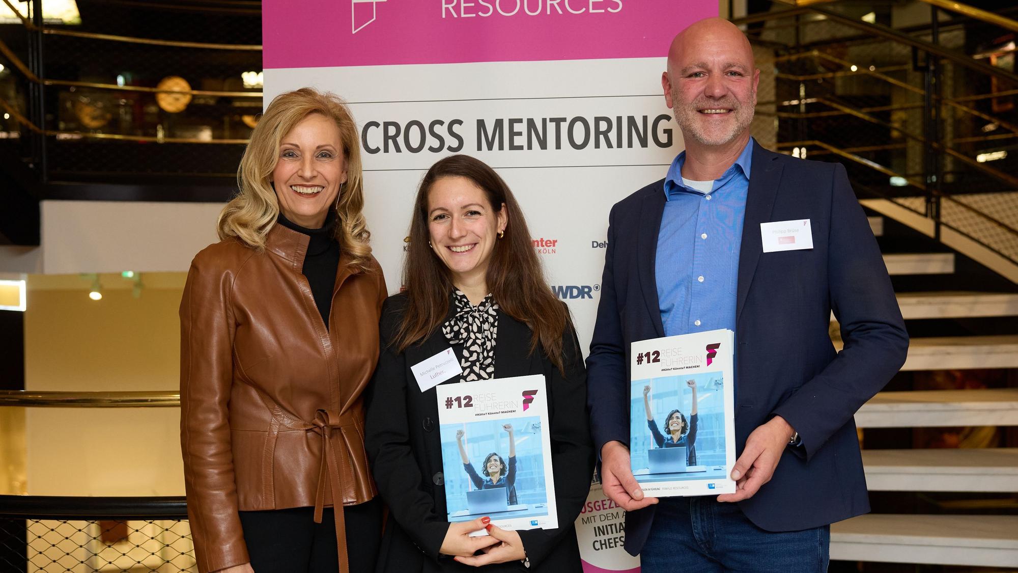 Michelle Petruzzelli und Philipp Brüse stehen gemeinsam mit Ulrike Lubek, Direktorin des LVR und Schirmherrin des Programms, vor einer Werbewand von Female Resources.