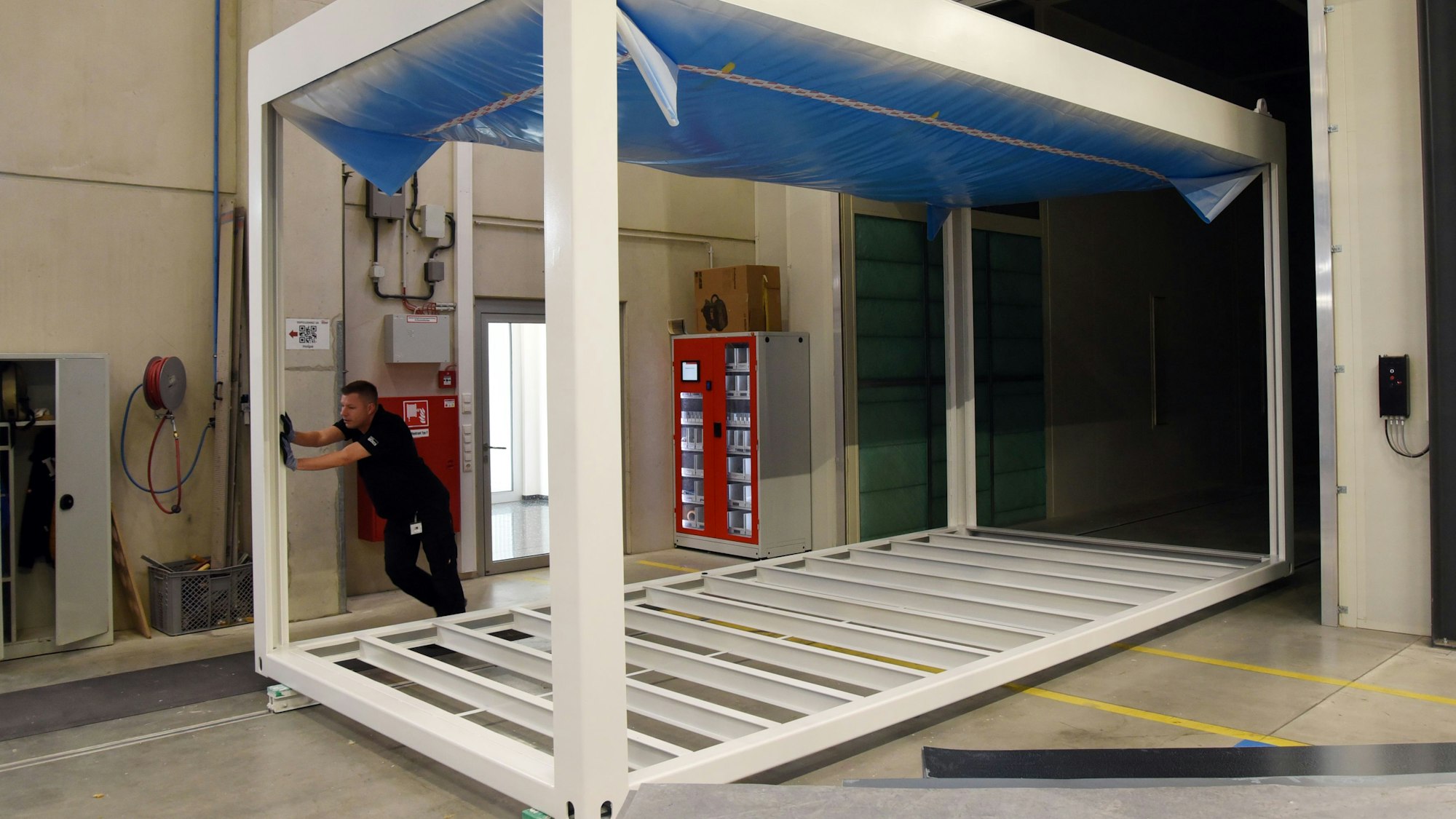 Von Hand und nahezu mühelos zieht Vorarbeiter Daniel Hähner bei Pro-Contain in Morsbach-Lichtenberg ein Containergerippe aus einer der Lackierstraßen. 2,3 Kilometer misst das Schienennetz in der Halle. Unser Foto zeigt den Mann bei der Arbeit.