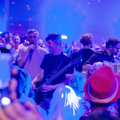 Die Musiker stehen mit ihren Instrumenten inmitten von kostümierten Menschen.