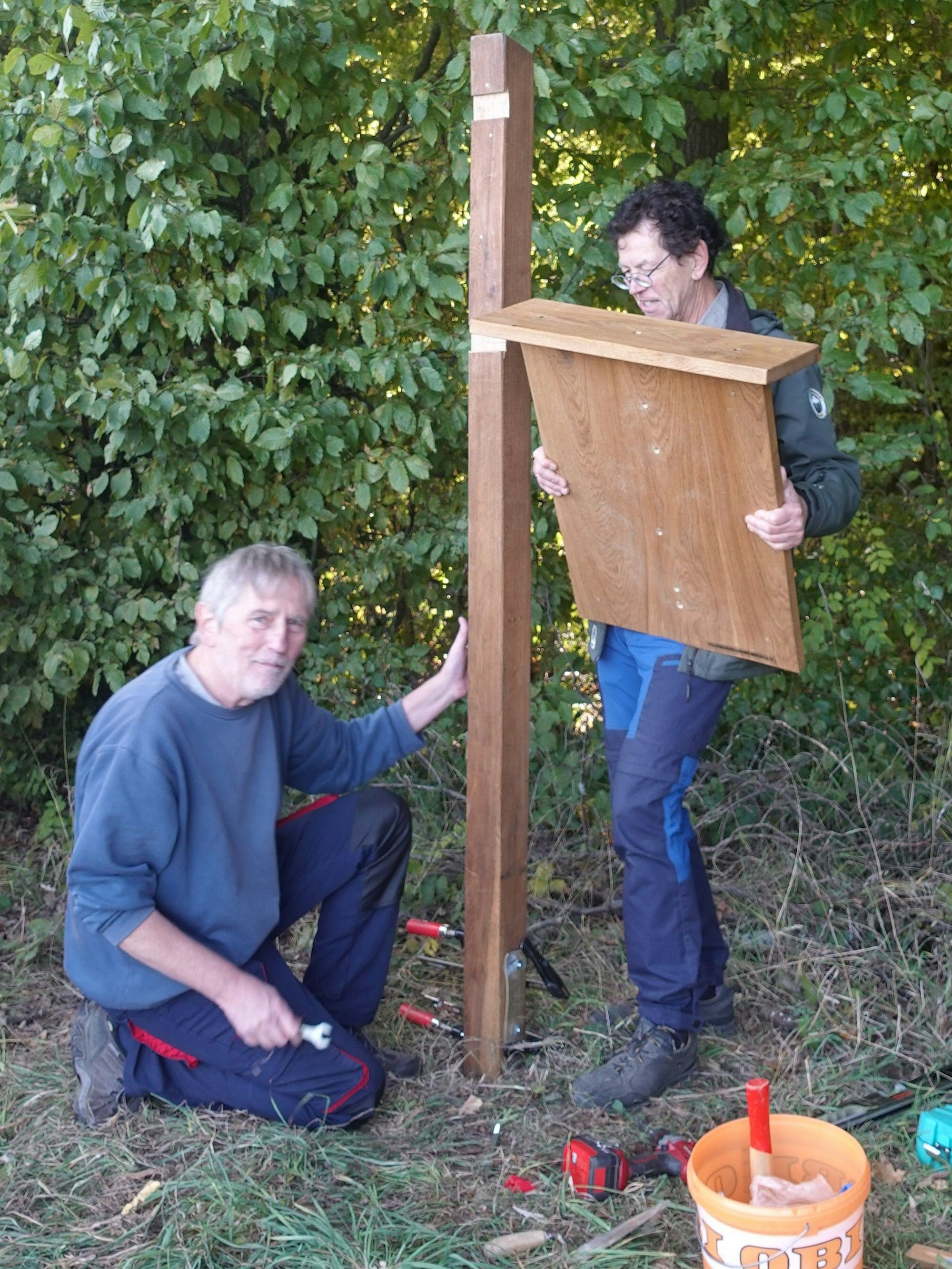 Ehrenamtler des Verkehrsvereins Much reparieren umgerissenen Wegweiser.