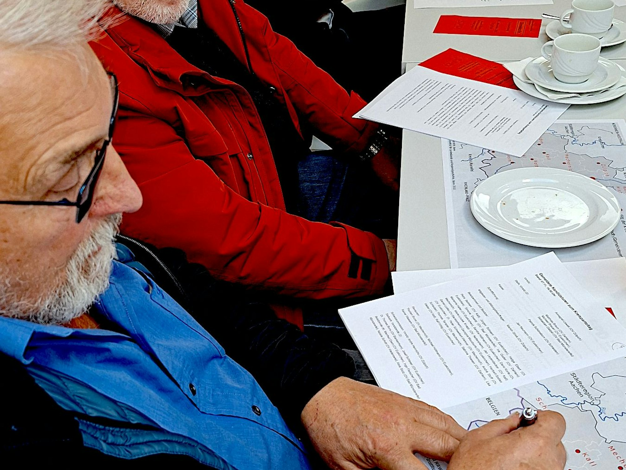 Mayer sitzt schreibend an einem Tisch.