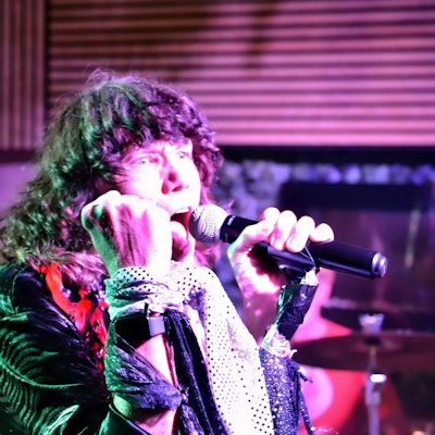 Der Sänger der Band trägt eine grüne Glitzerjacke.