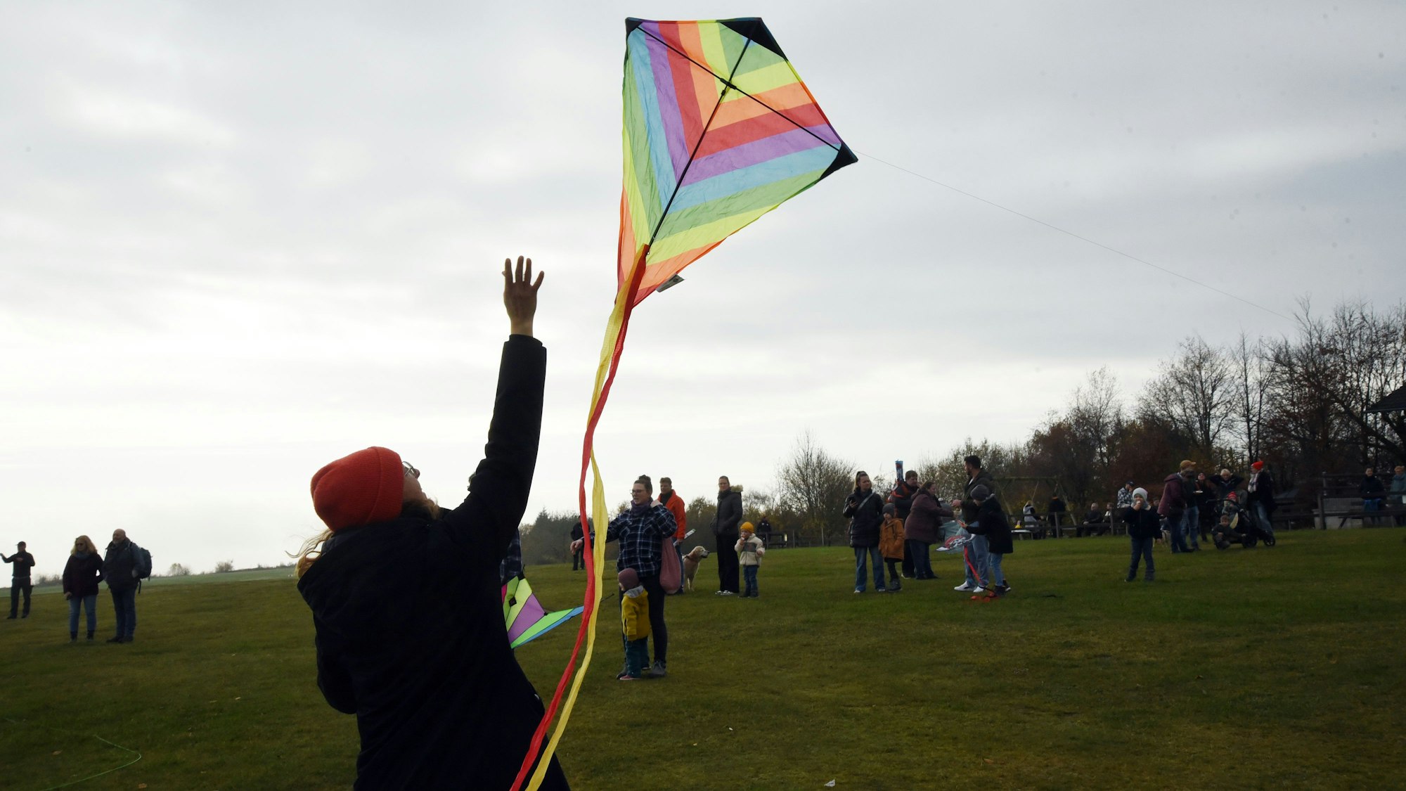 Eine Frau lässt einen bunten Drachen steigen.
