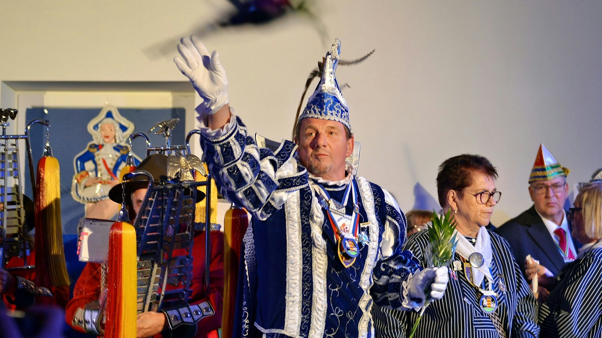 Emil Bolde im blauen Prinzenornat wirft einen Blumenstrauß ins Publikum.