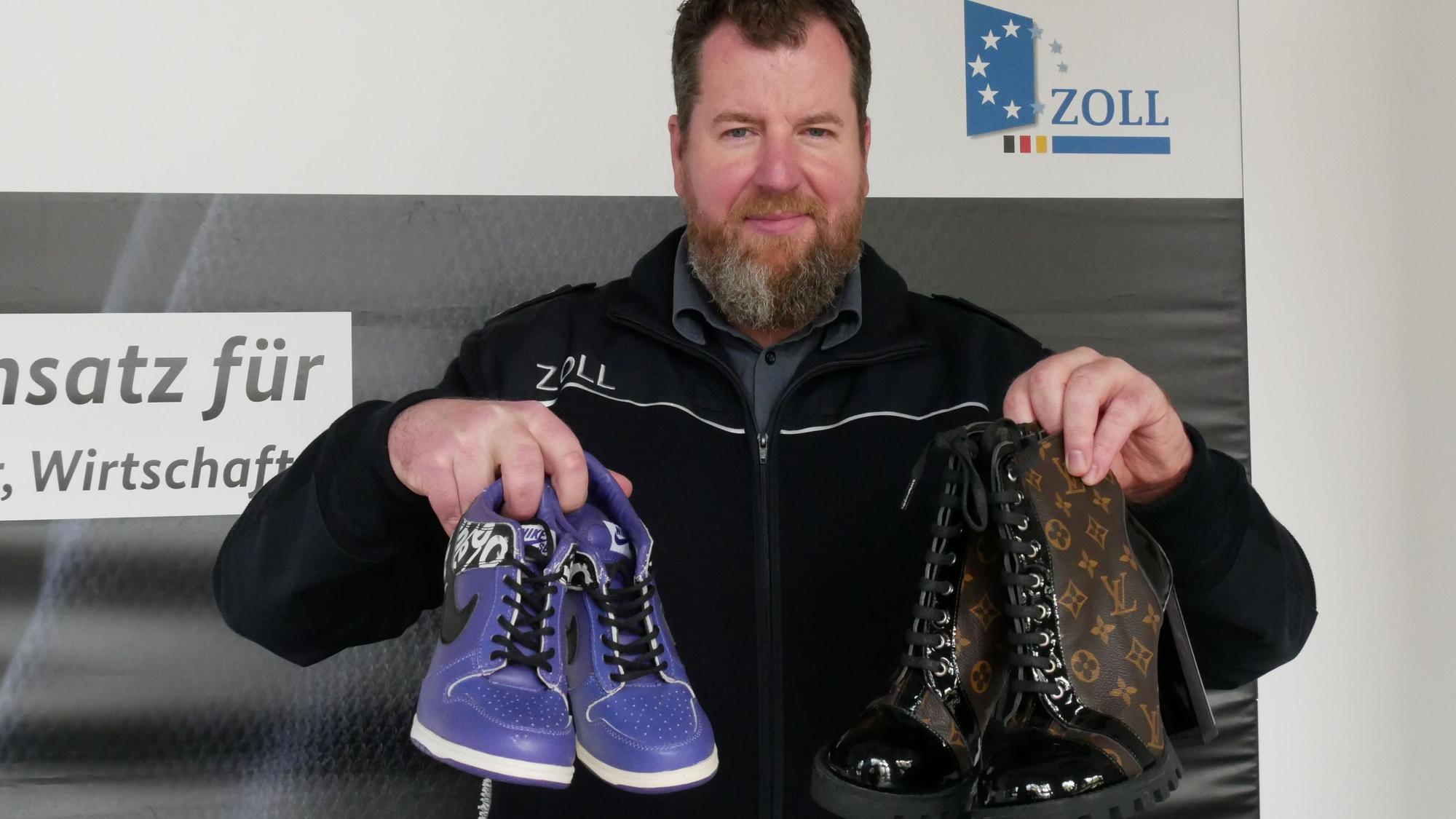 Zoll-Sprecher Jens Ahland hält gefälschte Schuhe in Händen.