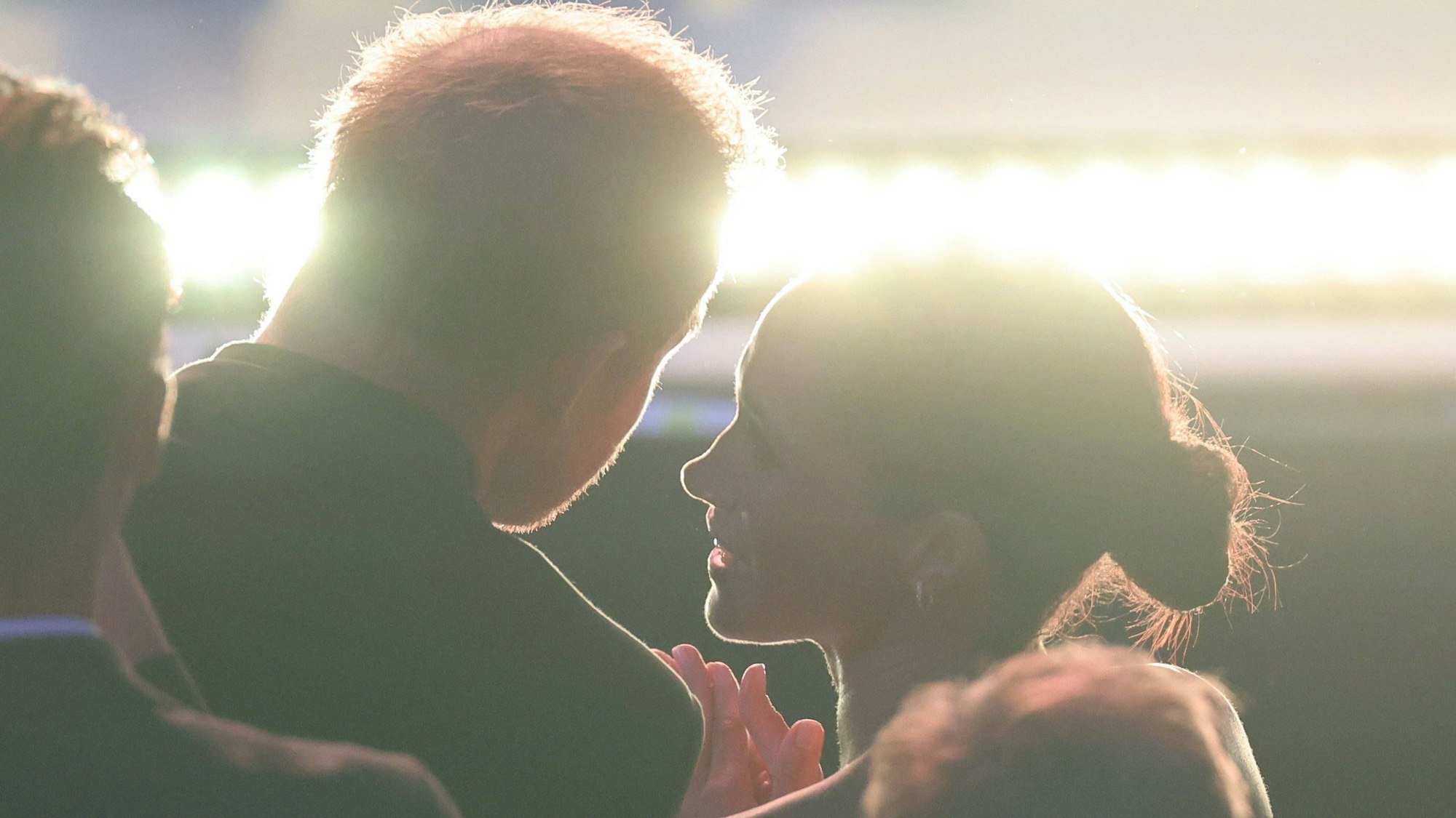 Prinz Harry und Meghan Markle in innigem Moment, vom Gegenlicht umrahmt.