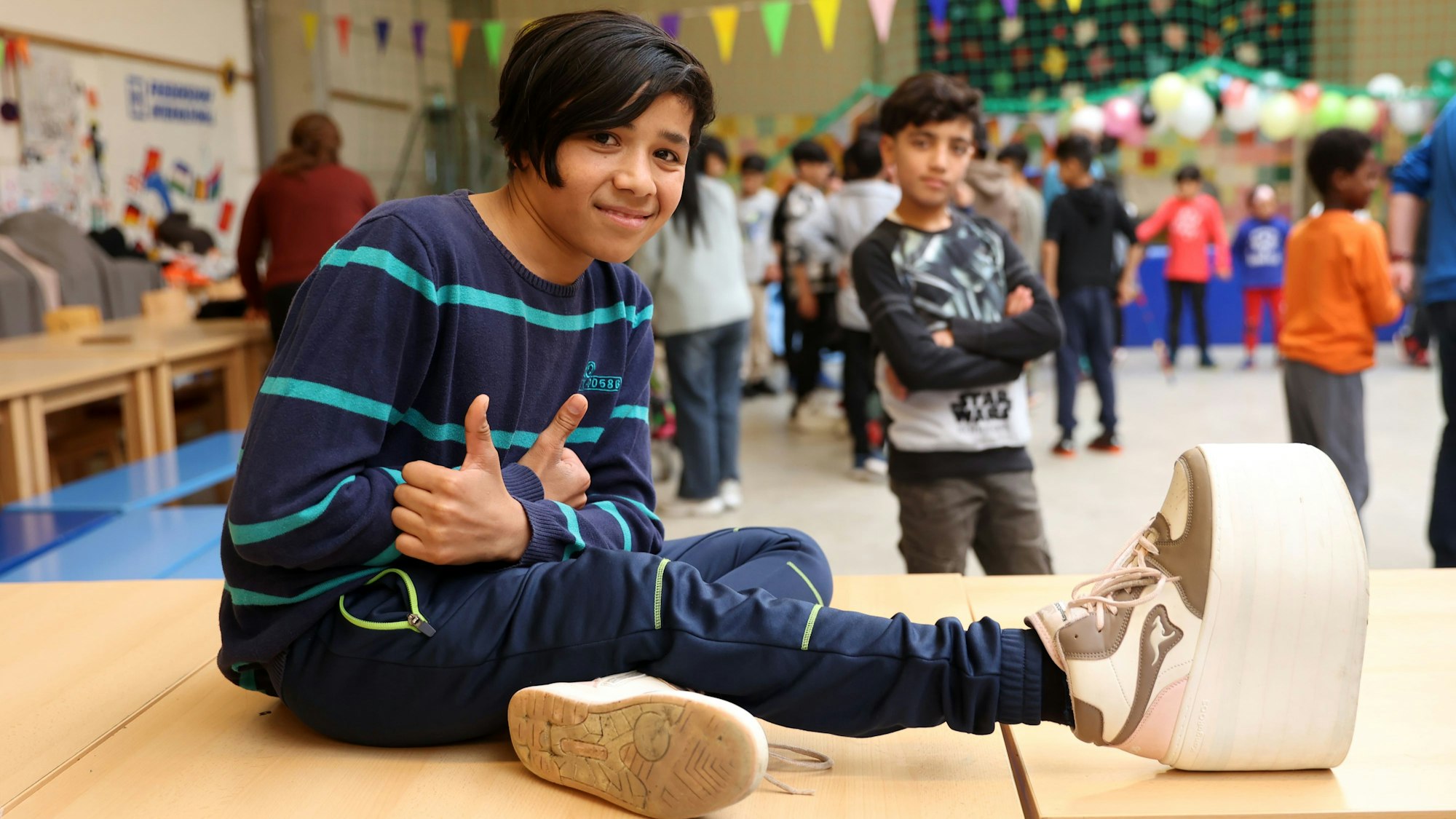 Hasibullah sitzt beim Abschiedsfest für die Rückkehrkinder in der Turnhalle