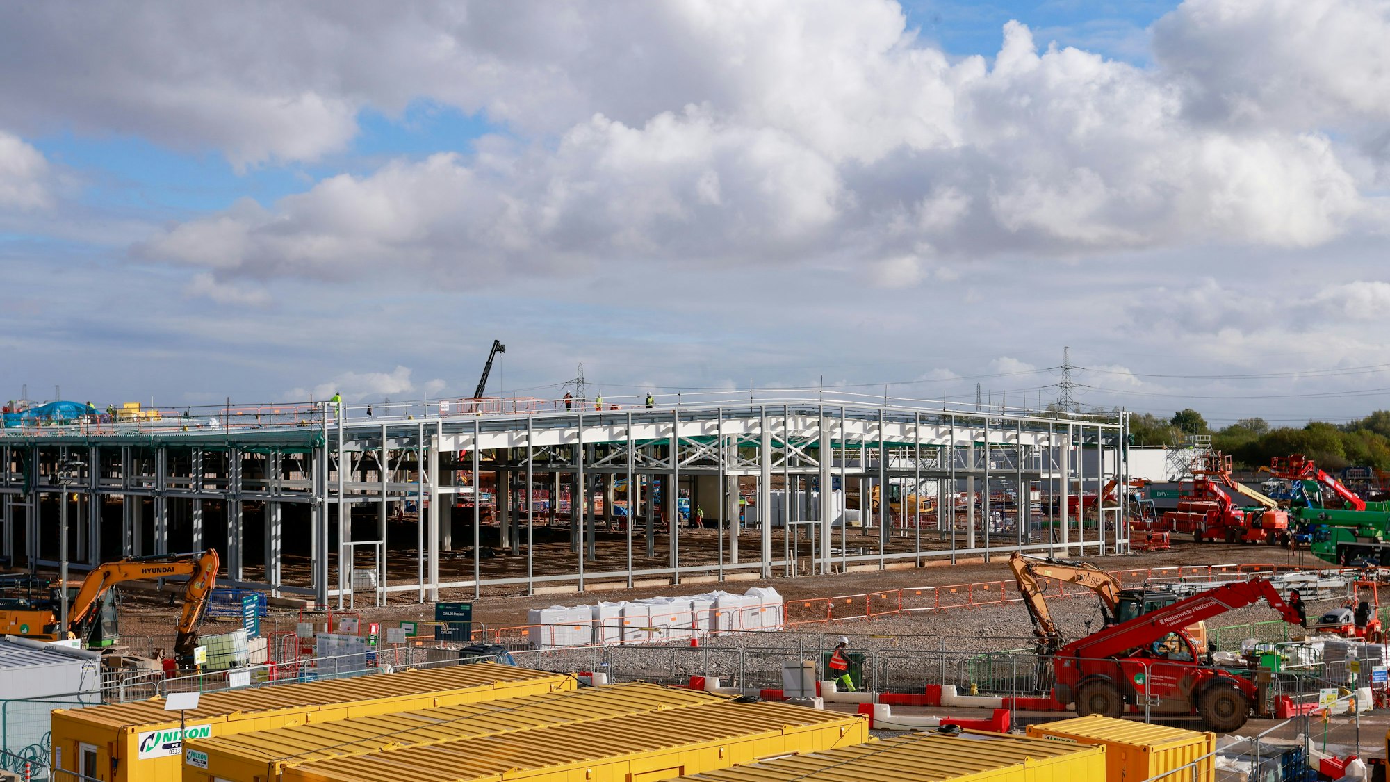 Rohbau eines Gebäudes mit Baustellenfahrzeugen davor.
