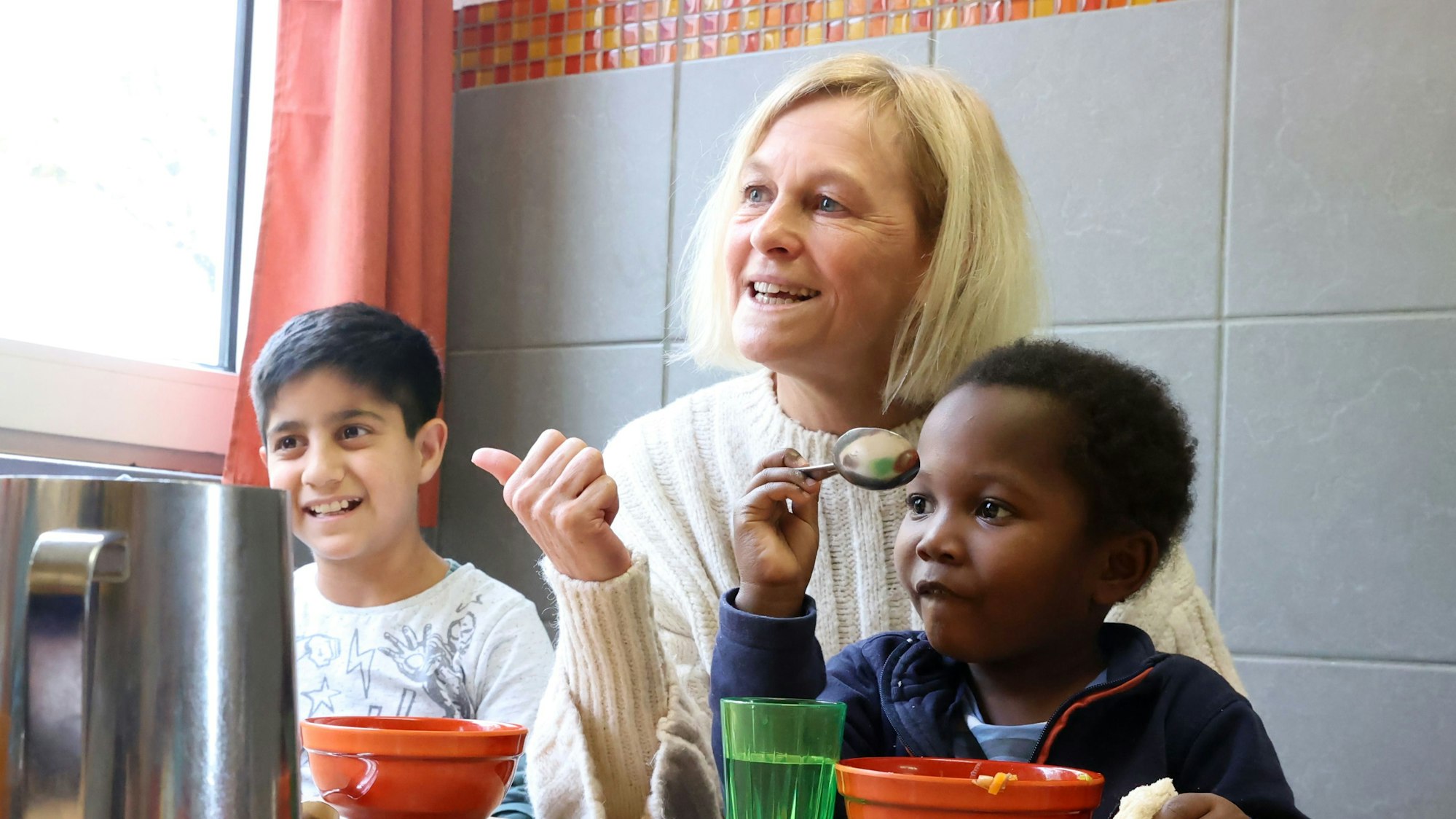 Farid aus Afghanistan sowie Stelvio aus Angola sitzen mit Claudia Peppmüller am Esstisch.