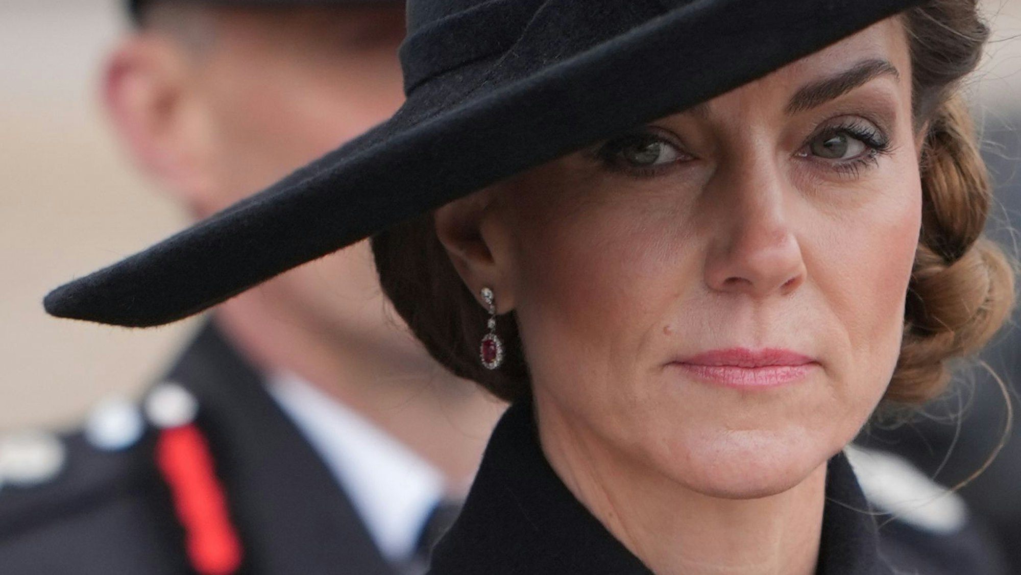Prinzessin Kate mit ernstem Blick und schwarzem Hut.