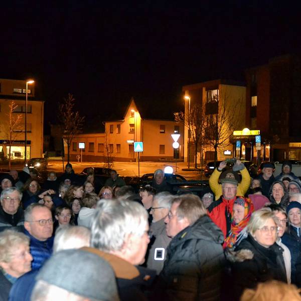 Eine große Gruppe Menschen hat sich um einen Redner versammelt.