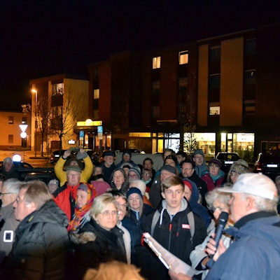 Eine große Gruppe Menschen hat sich um einen Redner versammelt.