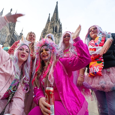 Jecken aus der Eifel stehen zum Beginn der Karnevalssession vor dem Dom für ein Foto zusammen.