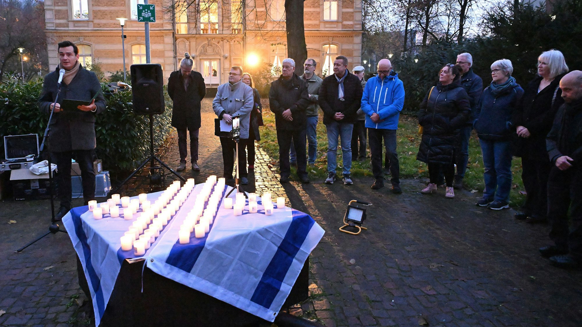 Die Menschen stehen im Kreis, der Bürgermeister hält eine Rede.