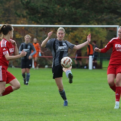 Anne Drehsen nimmt den Ball mit ausgestrecktem Fuß an. Von beiden Seiten nähern sich Gegenspielerinnen.