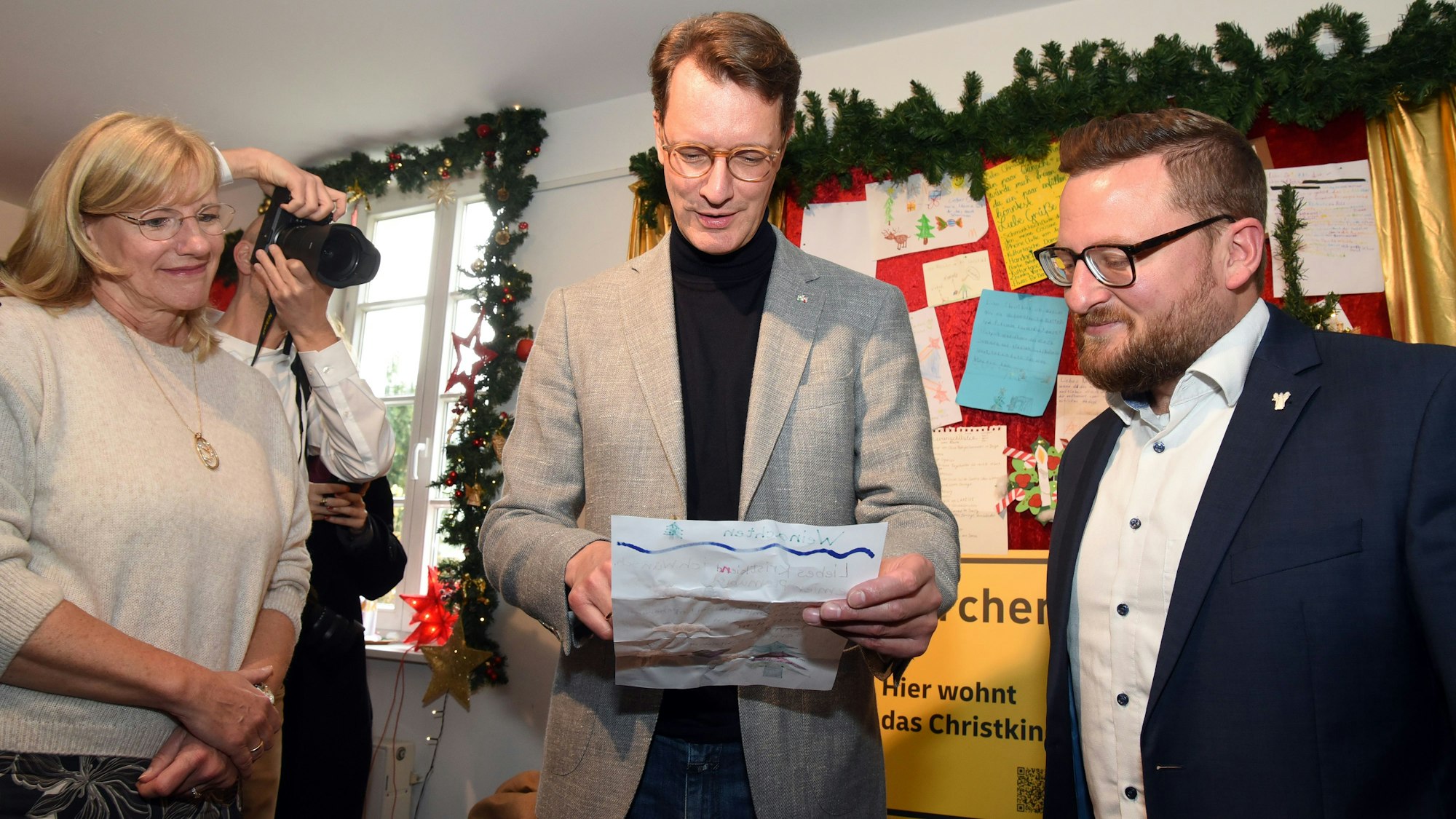 Ministerpräsident Wüst und Bürgermeister Miebach lesen einen Wunschzettel eines Kindes für das Christkind.
