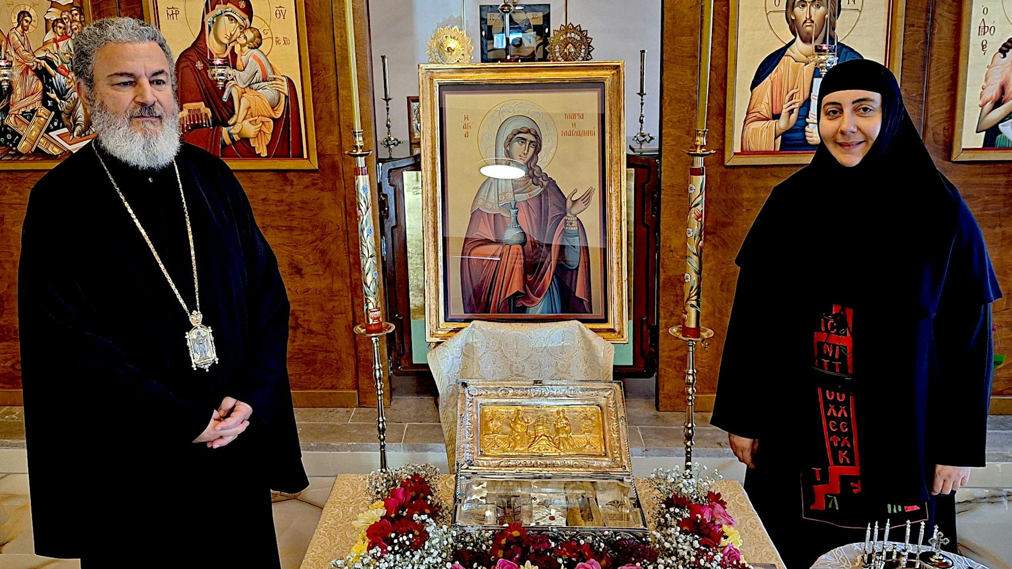 Zwei Vertreter der orthodoxen Kirche, Metropolit Isaak Barakat und Schwester Lukia, stehen links und rechts vom Reliquienschrein.