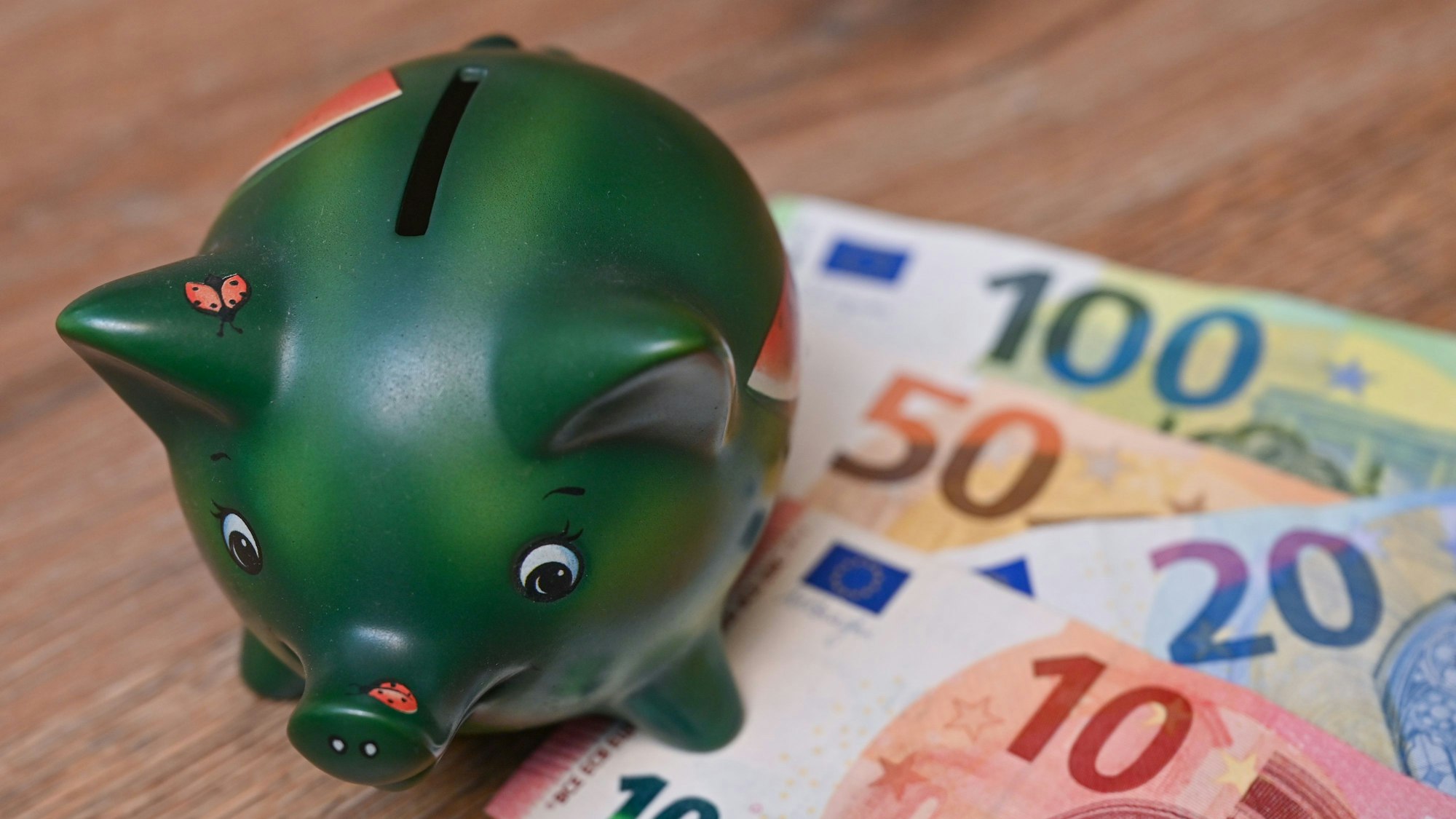 Ein Sparschwein steht auf einem Tisch neben Eurobanknoten. (Symbolbild)