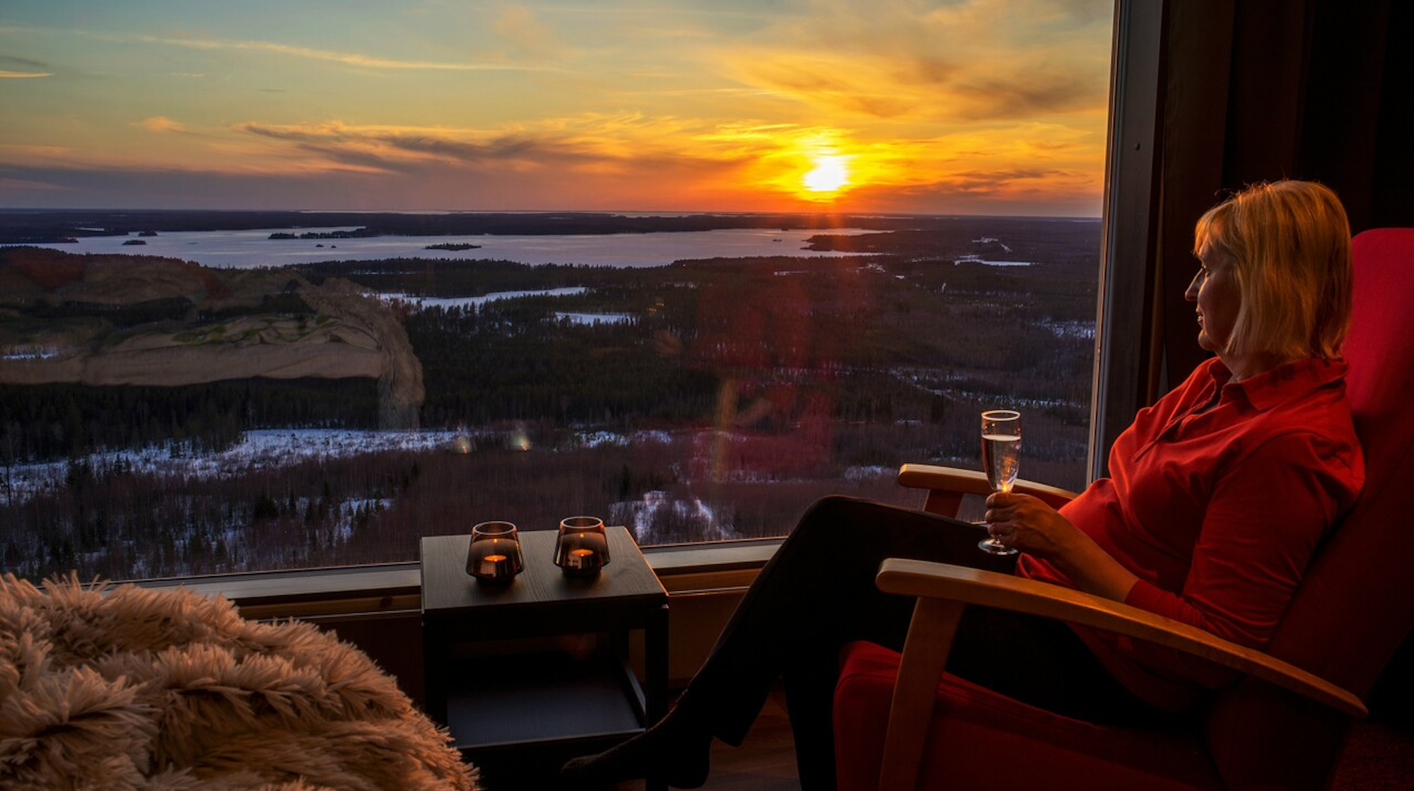 Eine Frau sitzt an einem Fenster und genießt die Aussicht auf das Arctic Lakeland.