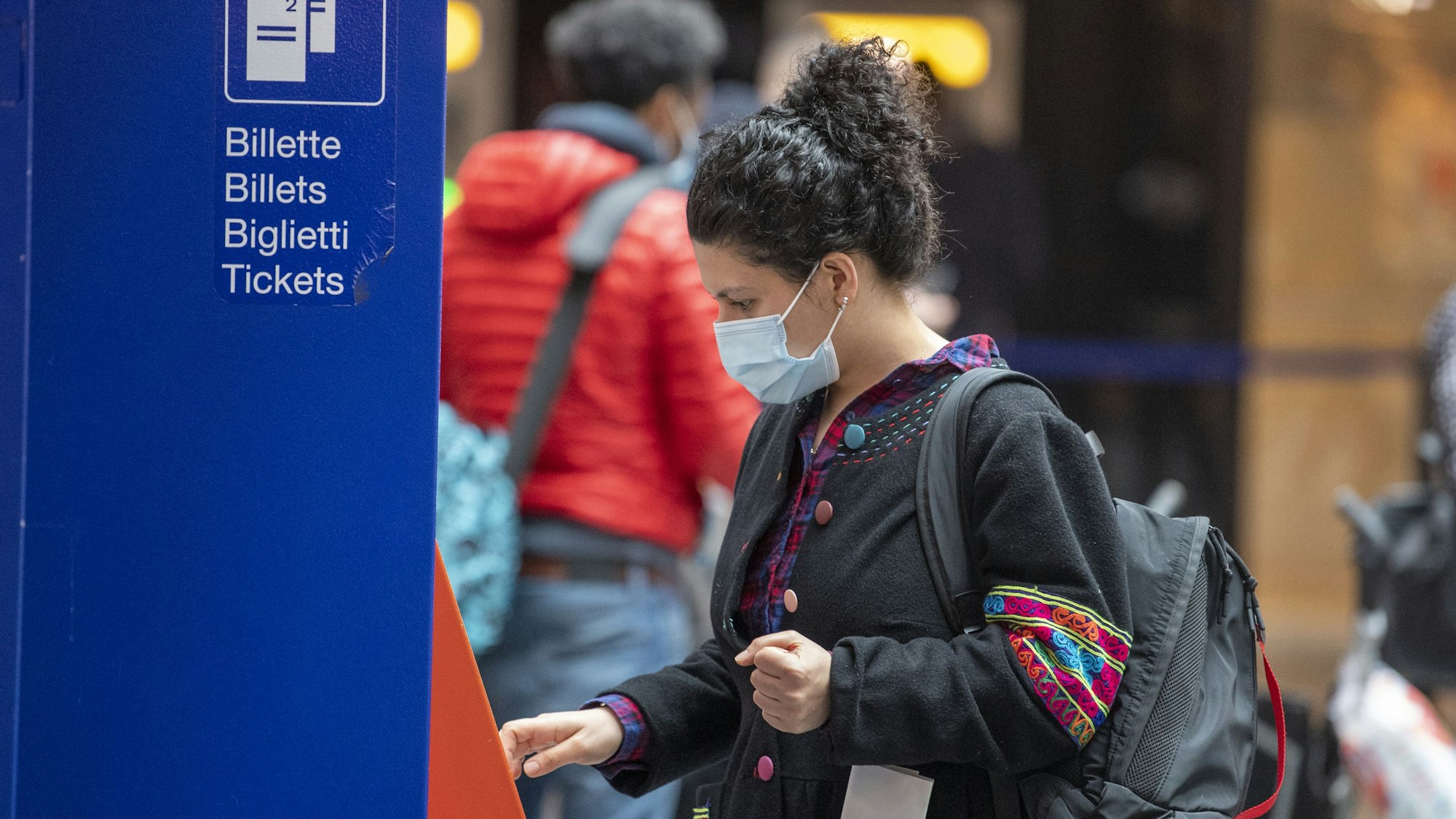 Eine Reisende mit Maske kauft sich an einem Fahrkartenautomaten im Bahnhof ein Ticket. Foto: picture alliance/dpa/KEYSTONE